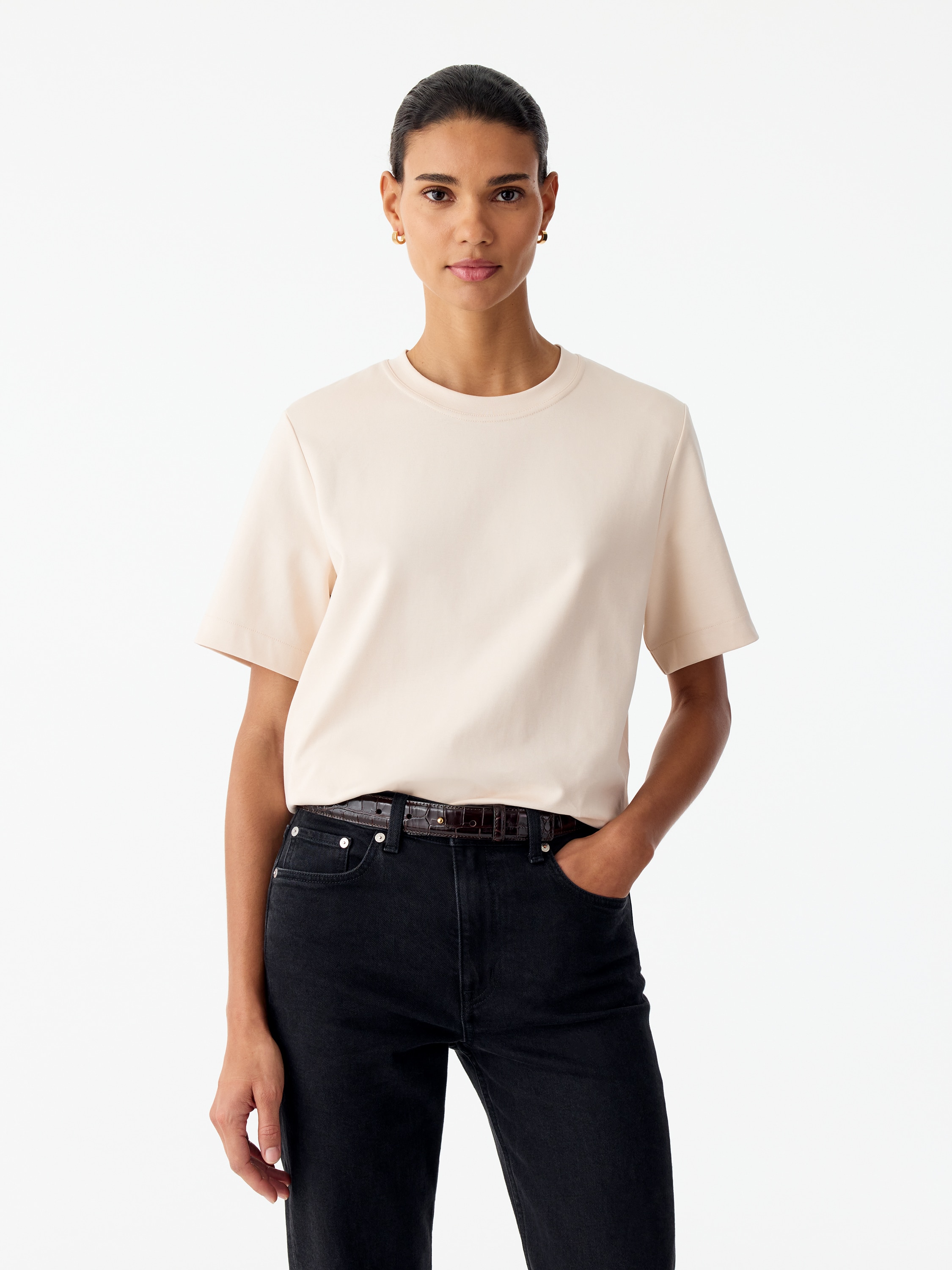 Ein cremefarbenes T-Shirt ist von vorne zu sehen und verfÃ¼gt Ã¼ber einen klassischen Rundhalsausschnitt sowie kurze, locker geschnittene Ãrmel. Das KleidungsstÃ¼ck liegt flach und zeigt seine Regular-Fit-Silhouette sowie die sauberen, minimalistischen NÃ¤hte an Saum und ÃrmelabschlÃ¼ssen.
