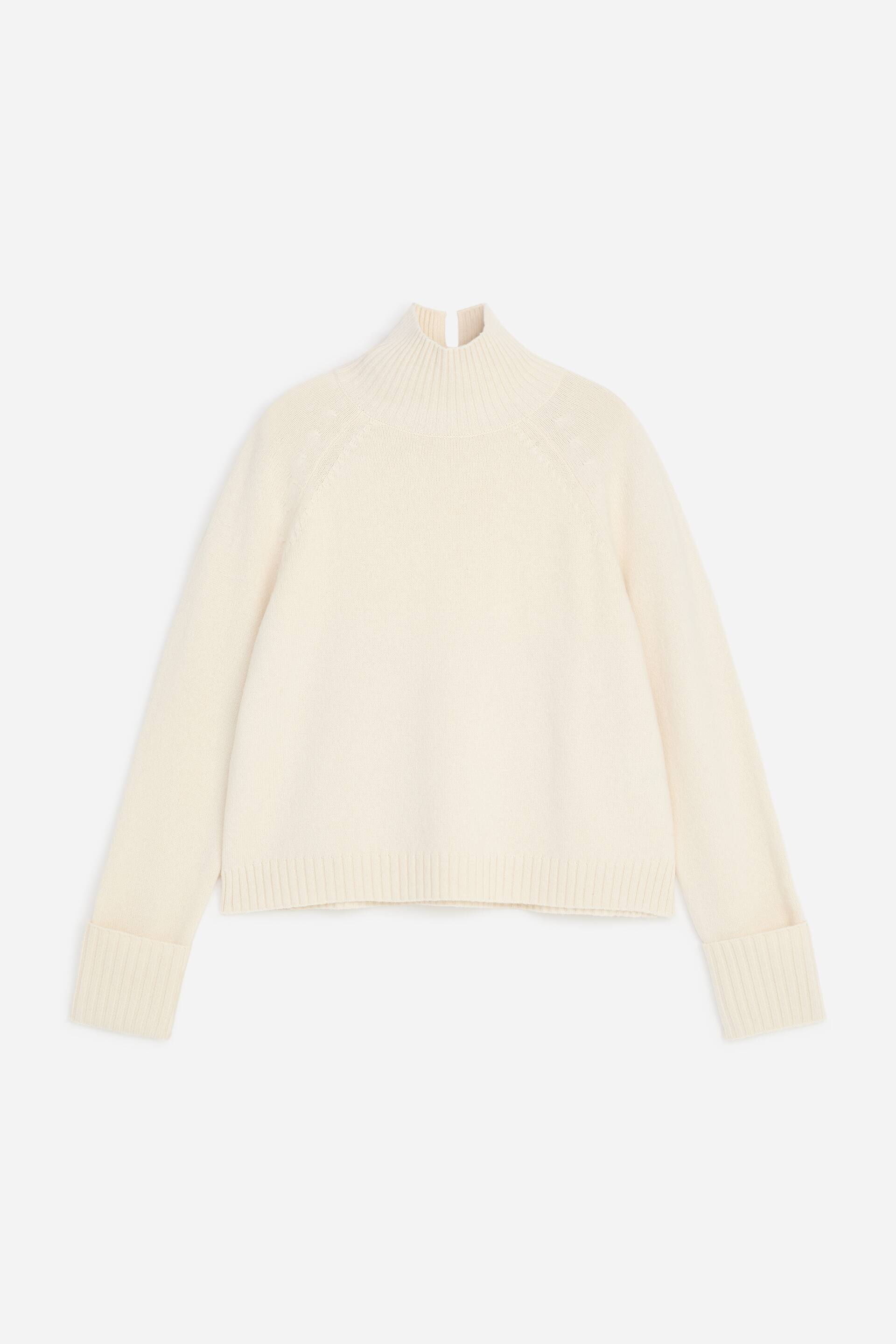 Ver imagen más grande: Se muestra por delante un jersey de punto de color crema, con cuello alto vuelto de canalé con abertura trasera, mangas raglán y puños anchos plegados de canalé. El jersey presenta un corte clásico con bajo de canalé.