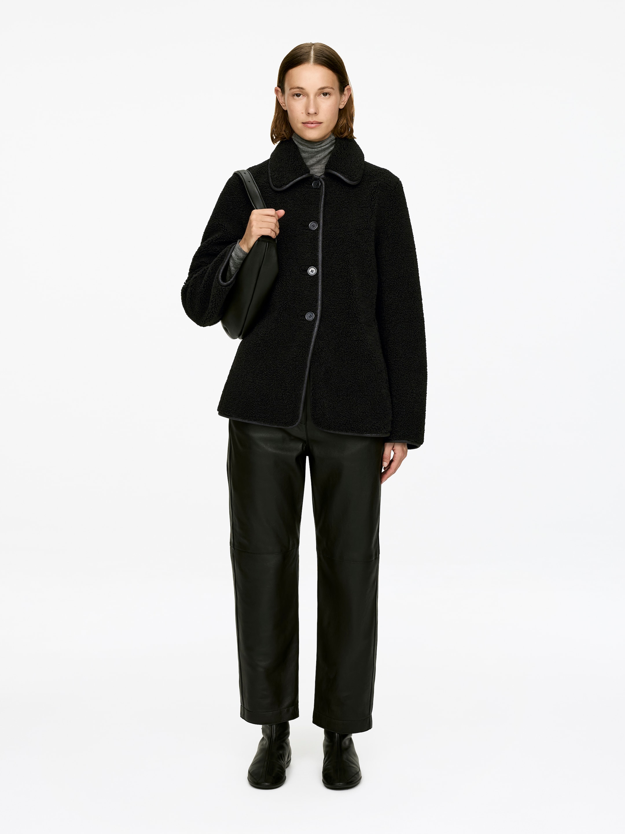 View larger image: A single-breasted pile jacket, featuring a classic collar, button closure, single welt pockets, and contrasting trim, is being worn by the model. A grey turtleneck is visible underneath the jacket.