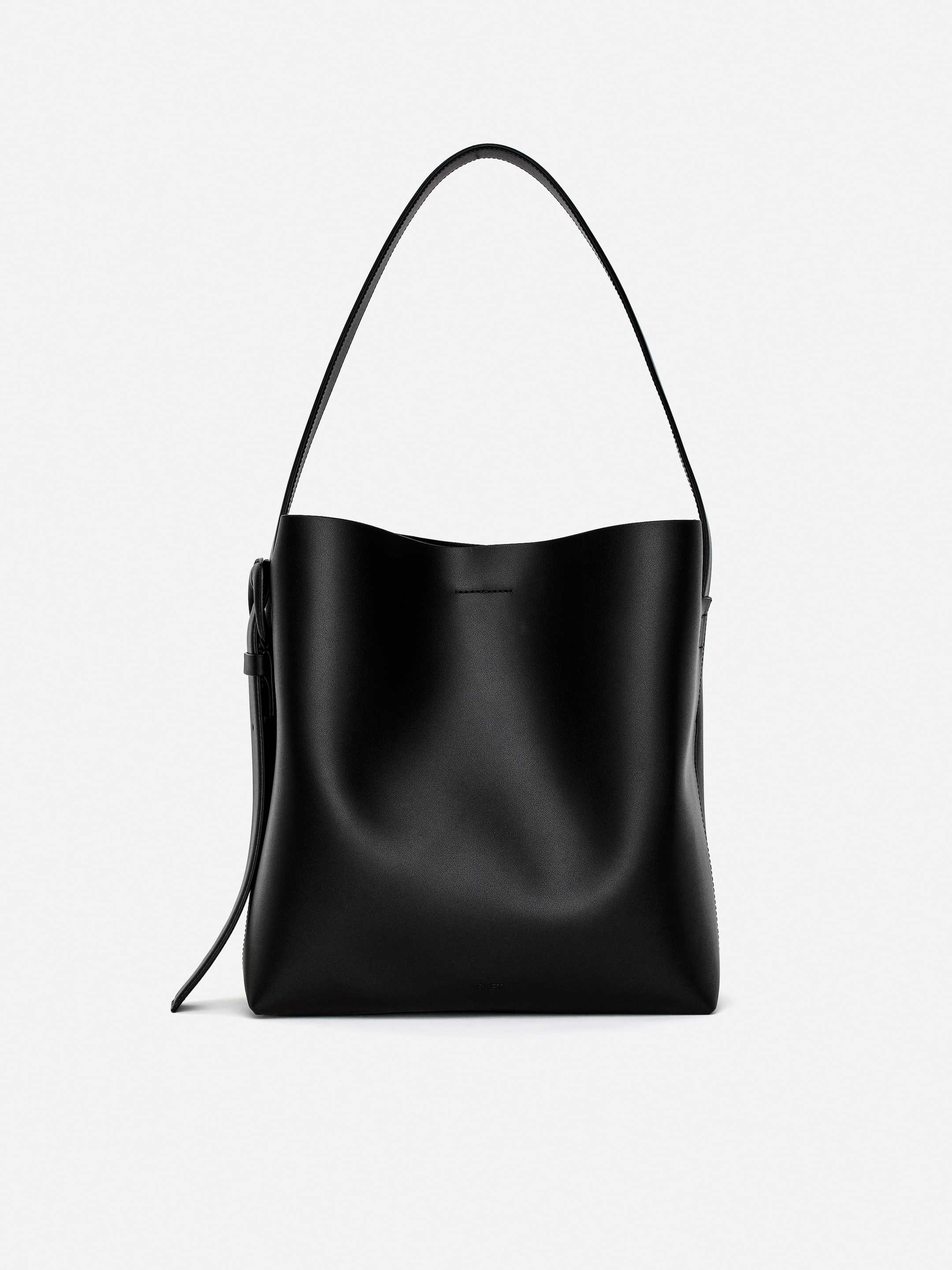 Vis større bilde: En svart tote bag viser frem sin front, med en strukturert, semi-rigid form og en glatt, matt finish. Dens romslige design er tydelig, og en bred skulderrem buer seg over vesken.
