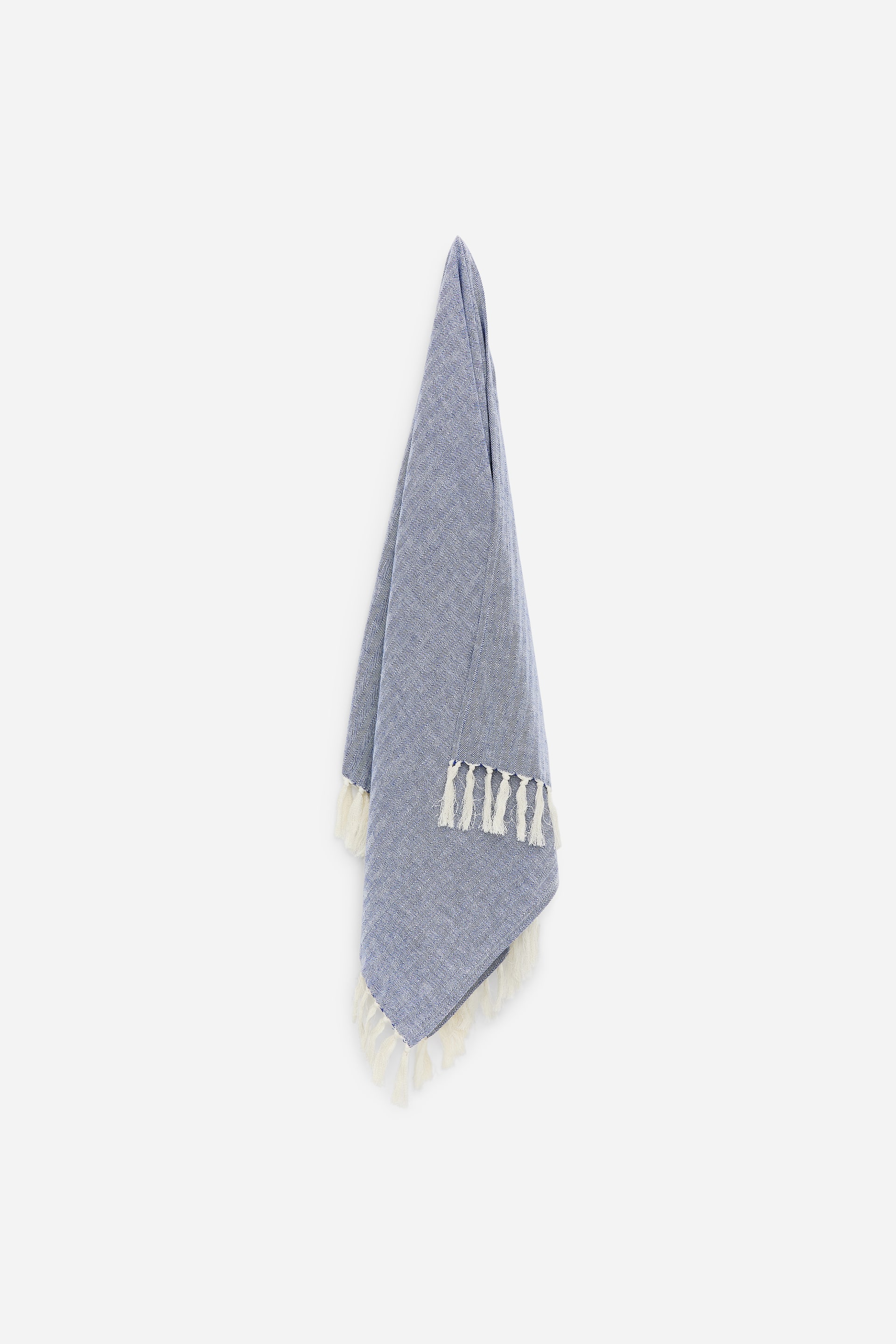 Visualizza l'immagine ingrandita: Un asciugamano da bagno in misto cotone e lino blu, intrecciato, è appeso, mostrando il suo lato anteriore. Presenta lunghe frange color crema lungo i suoi lati più corti.