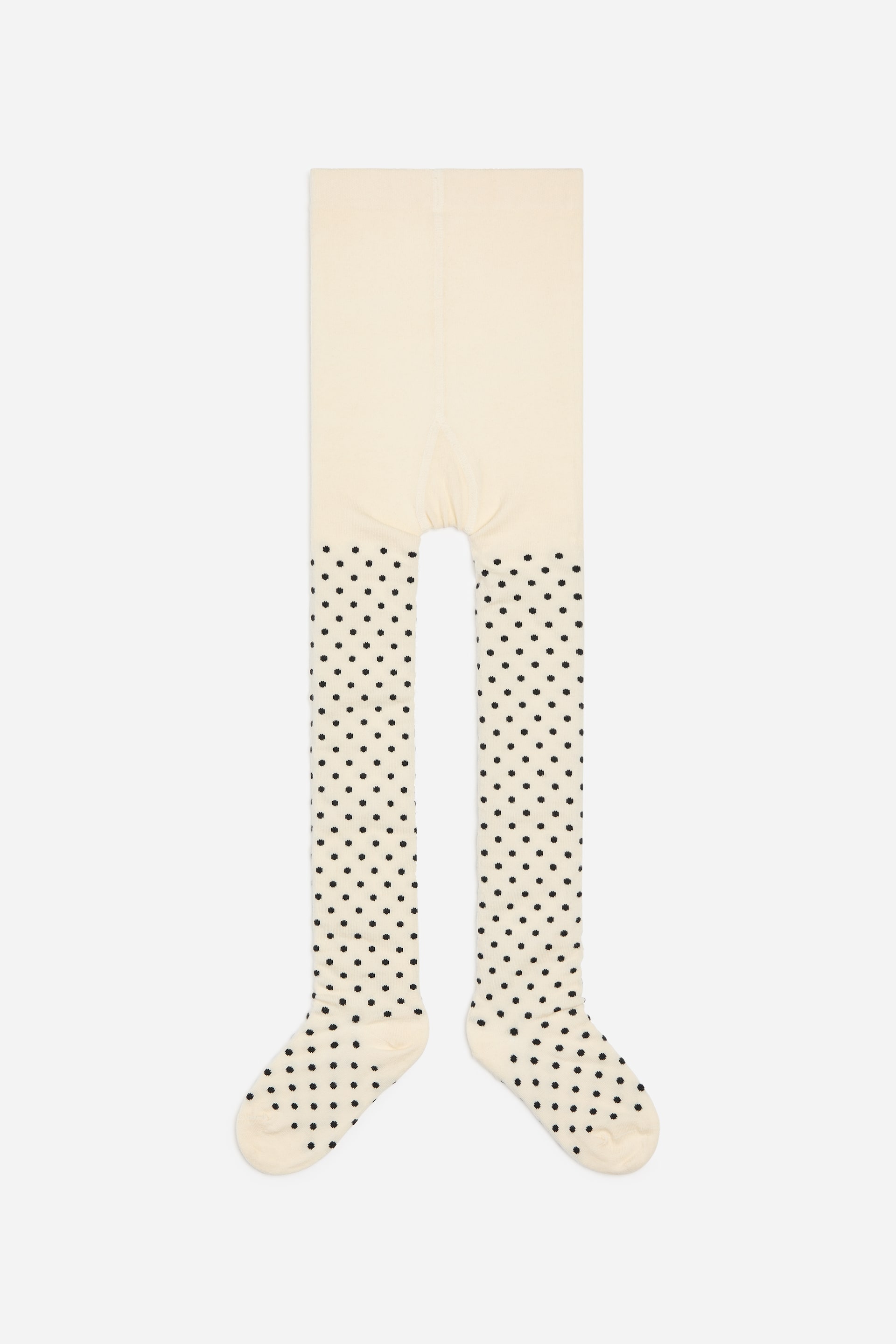 Agrandir l'image: Une paire de collants est présentée de face, avec un corps supérieur uni couleur crème. Les jambes et les pieds affichent une base crème à pois noirs, et les zones du talon et des orteils apparaissent renforcées en crème uni.