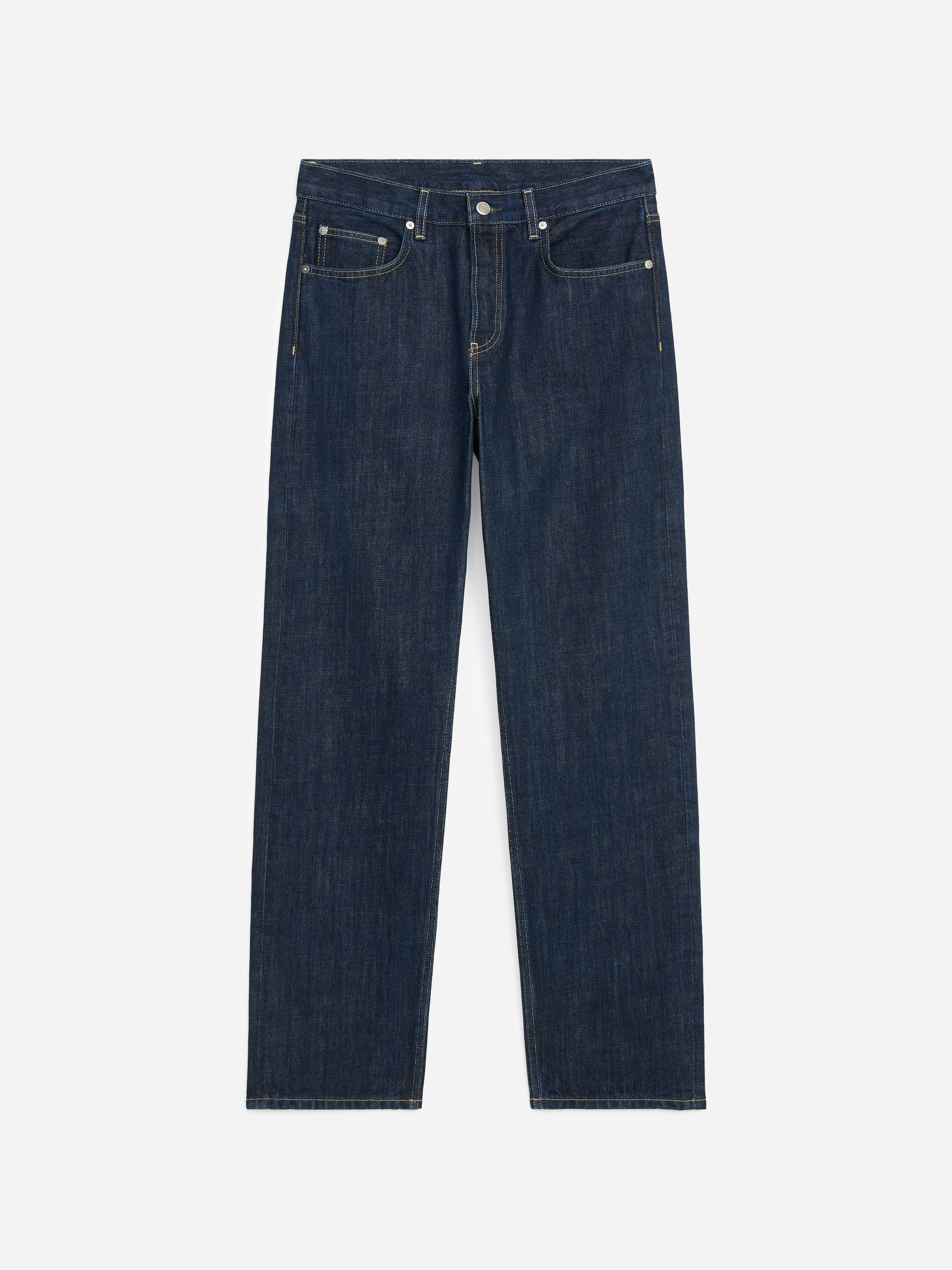 Diese gerade geschnittene blaue Denim-Jeans in dunkler Waschung wird vom Model getragen und zeichnet sich durch einen mittelhohen Bund sowie eine lockere Passform in voller Länge aus. Die Jeans ist mit einem in den Bund gesteckten marineblauen Rundhalspullover und schwarzen Lederschuhen kombiniert.