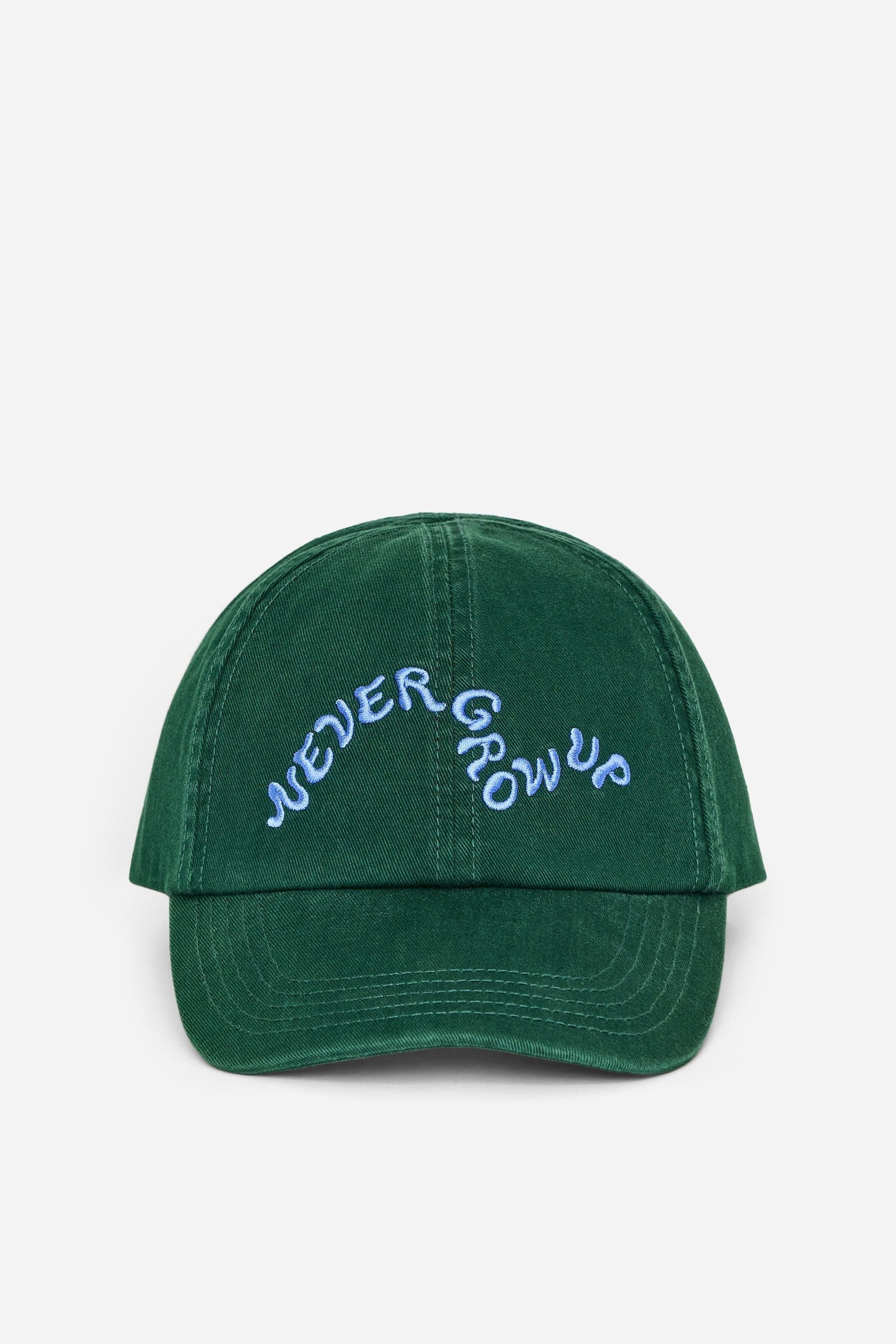 Ingrandisci l'immagine: Un cappellino in stile baseball presenta la sua parte anteriore, caratterizzata da un tessuto verde scuro. Il pannello frontale mostra un testo ricamato in azzurro chiaro che recita "NEVER GROW UP" in un carattere curvo e stilizzato.