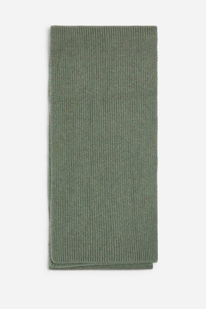 Ein moosgrÃ¼ner Strickschal ist in der Vorderansicht zu sehen und vertikal gefaltet, um sein strukturiertes, geripptes Design zu prÃ¤sentieren. Der Schal zeigt ein gleichmÃ¤Ãiges, vertikales Rippenstrickmuster mit sauberen, geraden Kanten. - 1
