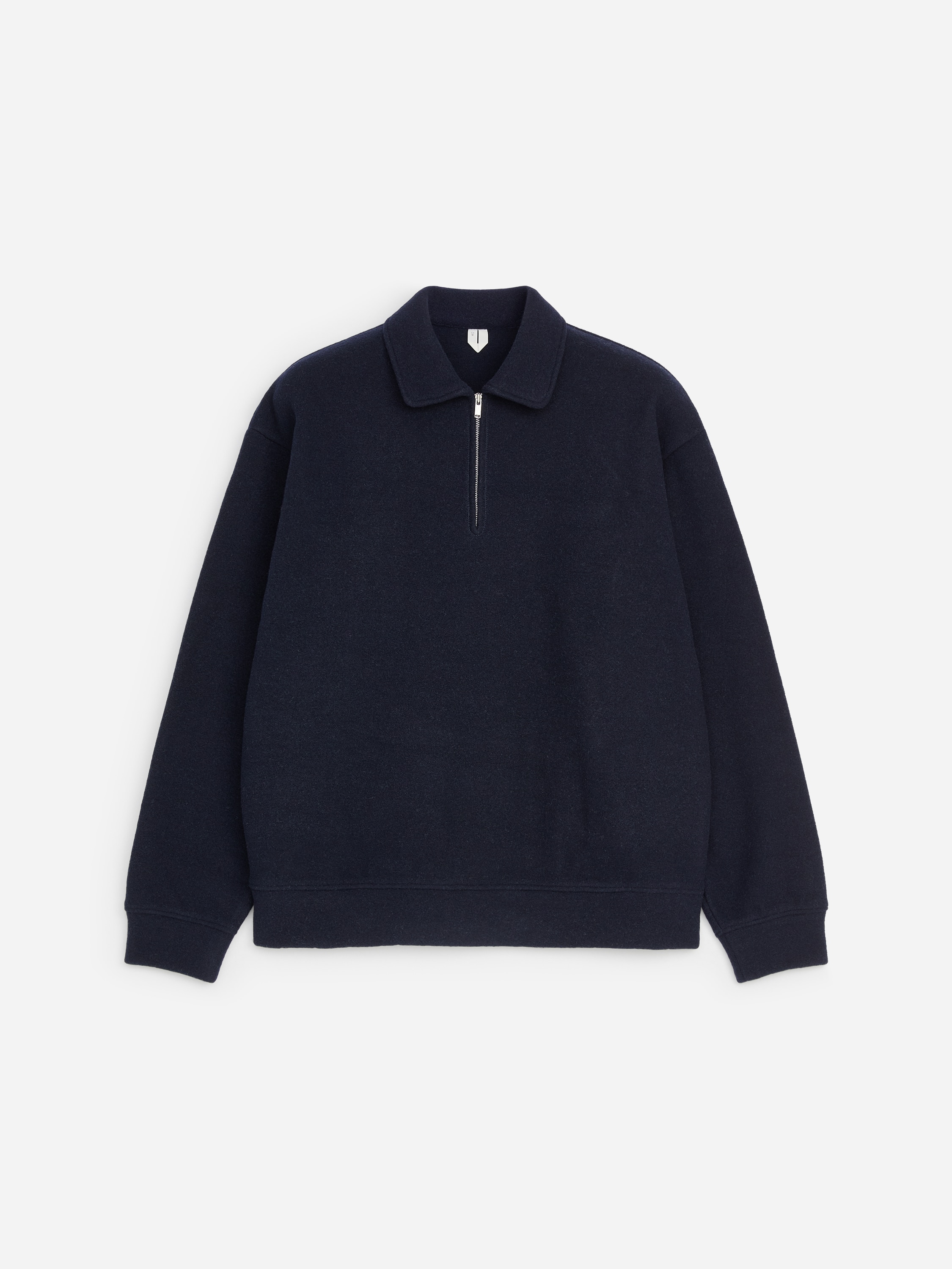 Ein dunkelnavyfarbener Half-Zip-Sweatshirt mit spitzem Kragen und silbernem Reißverschluss wird vom Model über einem weißen Rundhals-T-Shirt getragen. Der Sweatshirt hat gerippte Bündchen und einen gerippten Saum und wird mit einer blauen Jeans kombiniert.