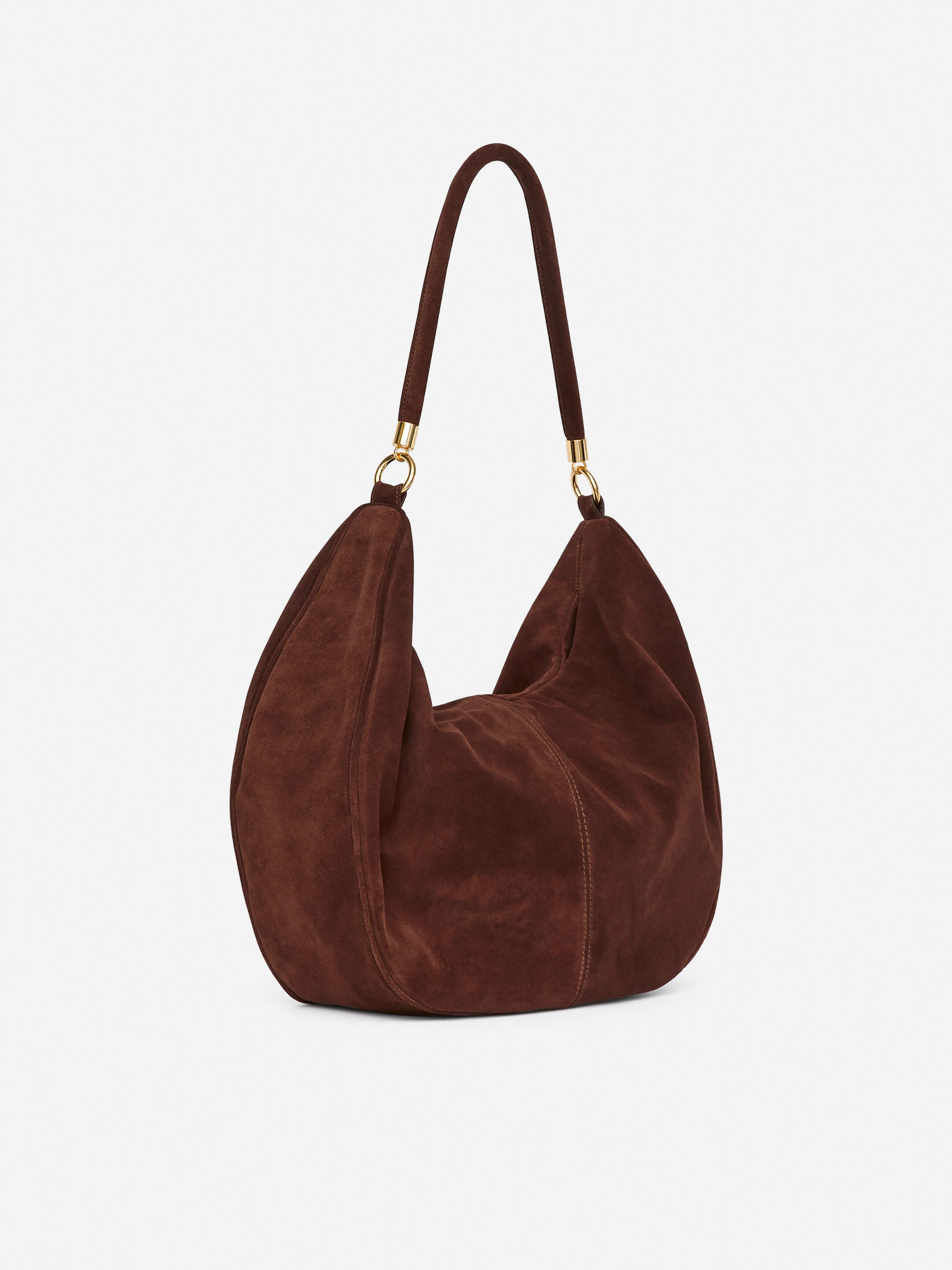 Grösseres Bild ansehen: Eine braune Wildleder-Schultertasche steht aufrecht und ist leicht nach rechts ausgerichtet. Sie zeichnet sich durch eine weiche, lässige Form mit sichtbaren Nähten und einem einzelnen gebogenen Schulterriemen aus, der mit goldfarbenen Beschlägen befestigt ist.