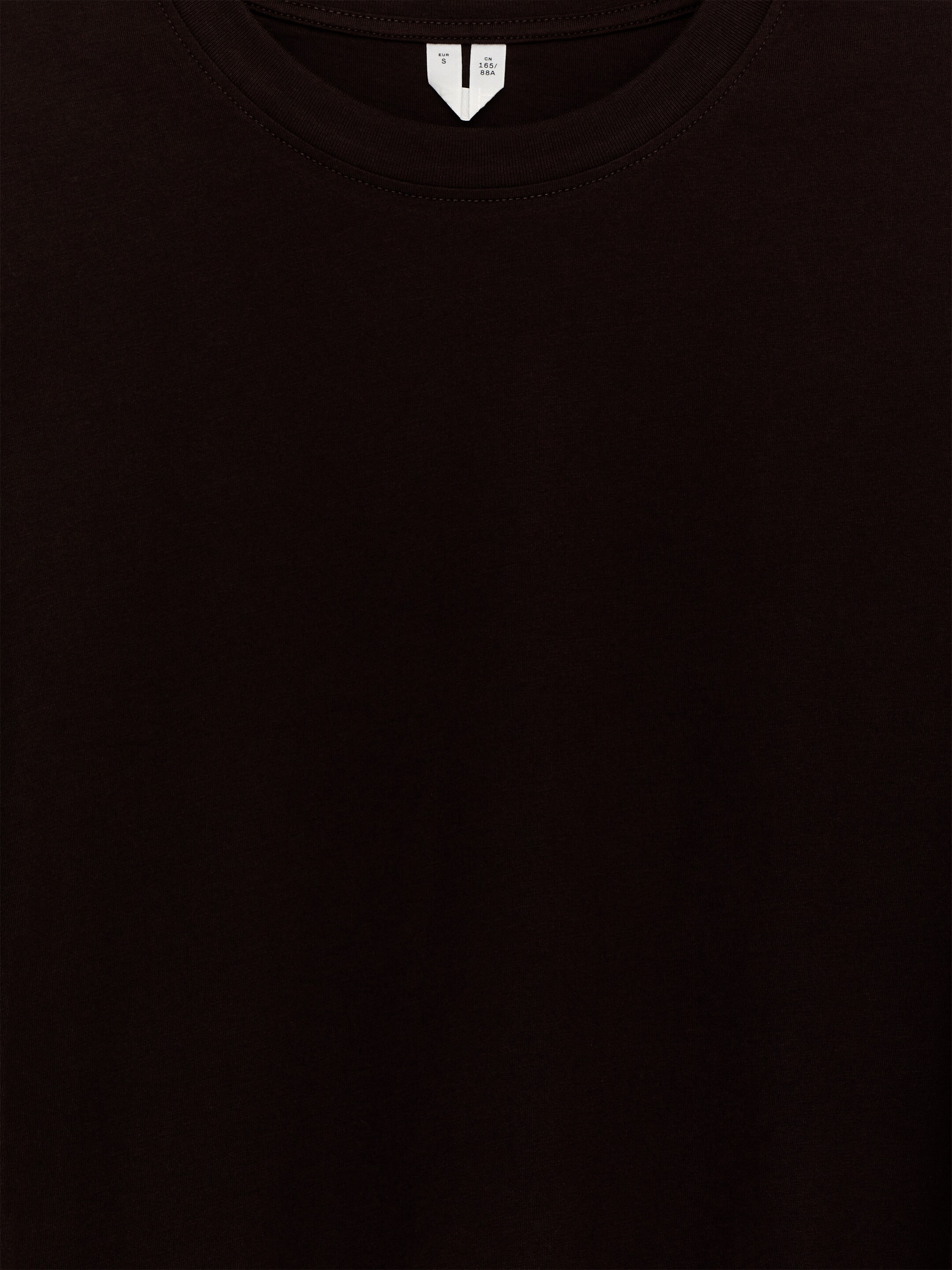 Agrandir l'image: Un T-shirt brun foncé est présenté de face, avec un col rond nervuré. Une petite étiquette de taille blanche avec du texte est visible à l'intérieur du dos du col.