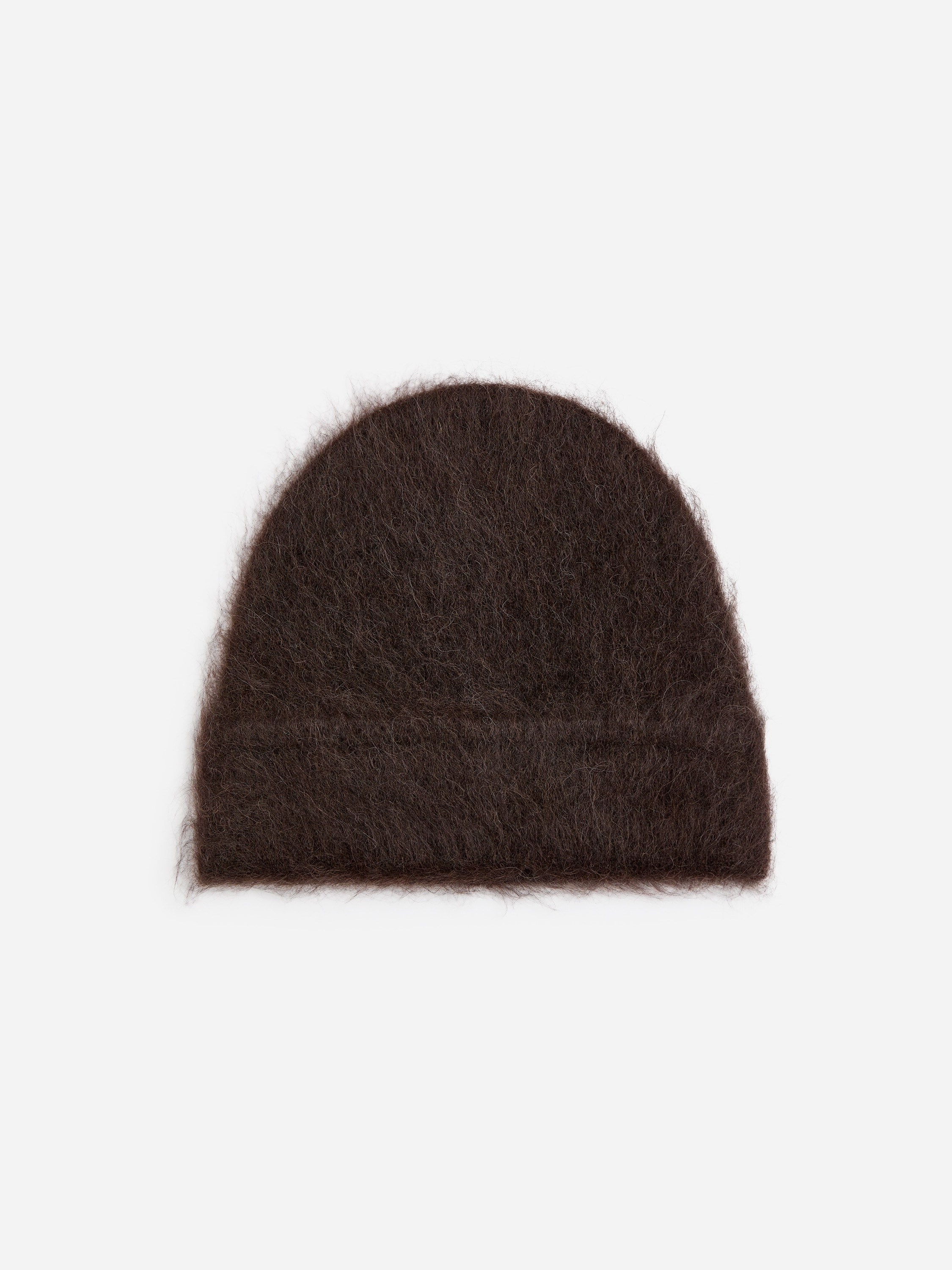 A dark brown, fluffy knitted beanie is being worn by the model, pulled low over the forehead. The brushed-texture beanie is styled with a matching dark brown puffer jacket and a high-neck ribbed sweater.