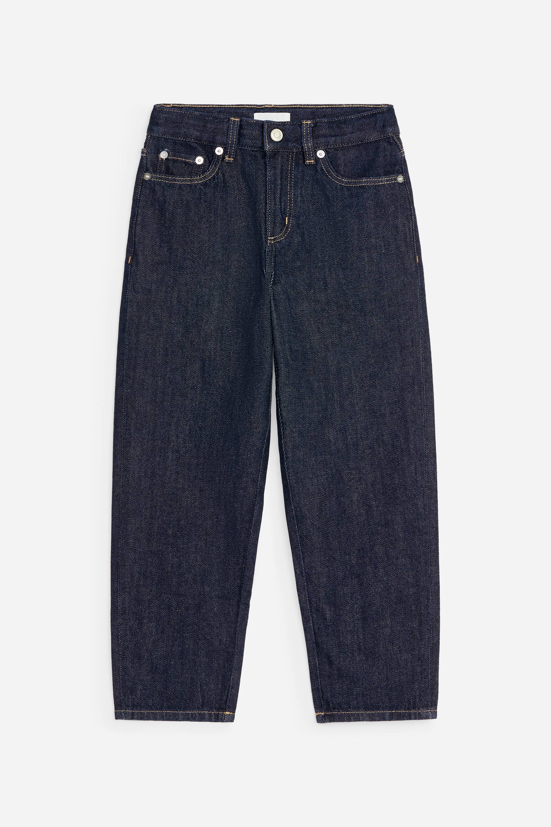 Vezi imaginea mai mare: O pereche de blugi din denim închis la culoare este prezentată din față, evidențiind o croială regular fit, cu crac drept și un design clasic cu cinci buzunare. Blugii prezintă cusături decorative contrastante portocalii, nituri metalice și închidere cu nasture la betelie.