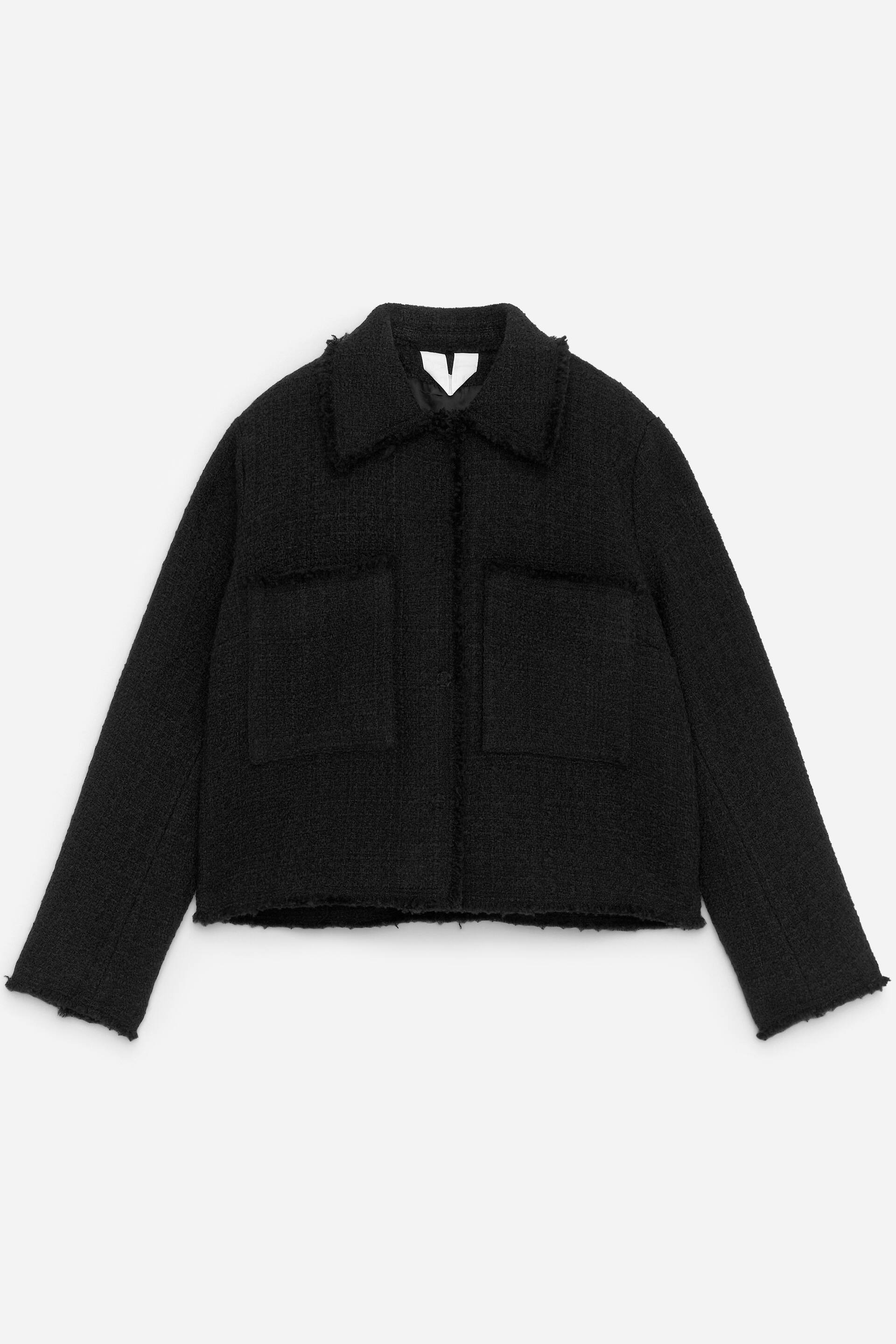 Visualizza immagine più grande: Una giacca nera corta è presentata in PRIMO PIANO, caratterizzata da un tessuto strutturato con bordi sfrangiati sul colletto classico, due tasche a toppa rettangolari sul petto, maniche lunghe e orlo dritto.