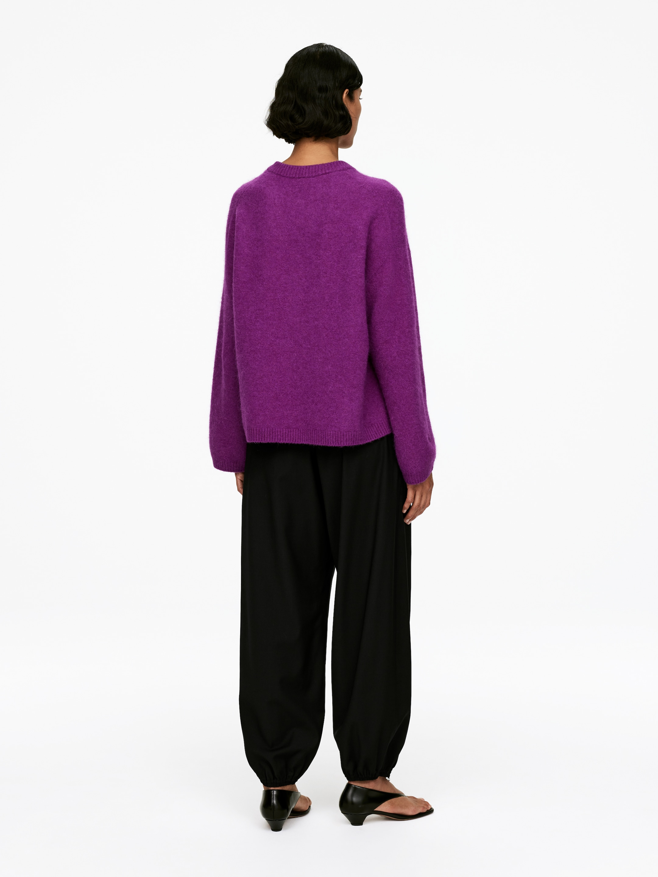 Agrandir l'image: Un pull violet duveteux avec une coupe ample et des finitions côtelées est porté par le mannequin, qui le présente associé à un pantalon noir.