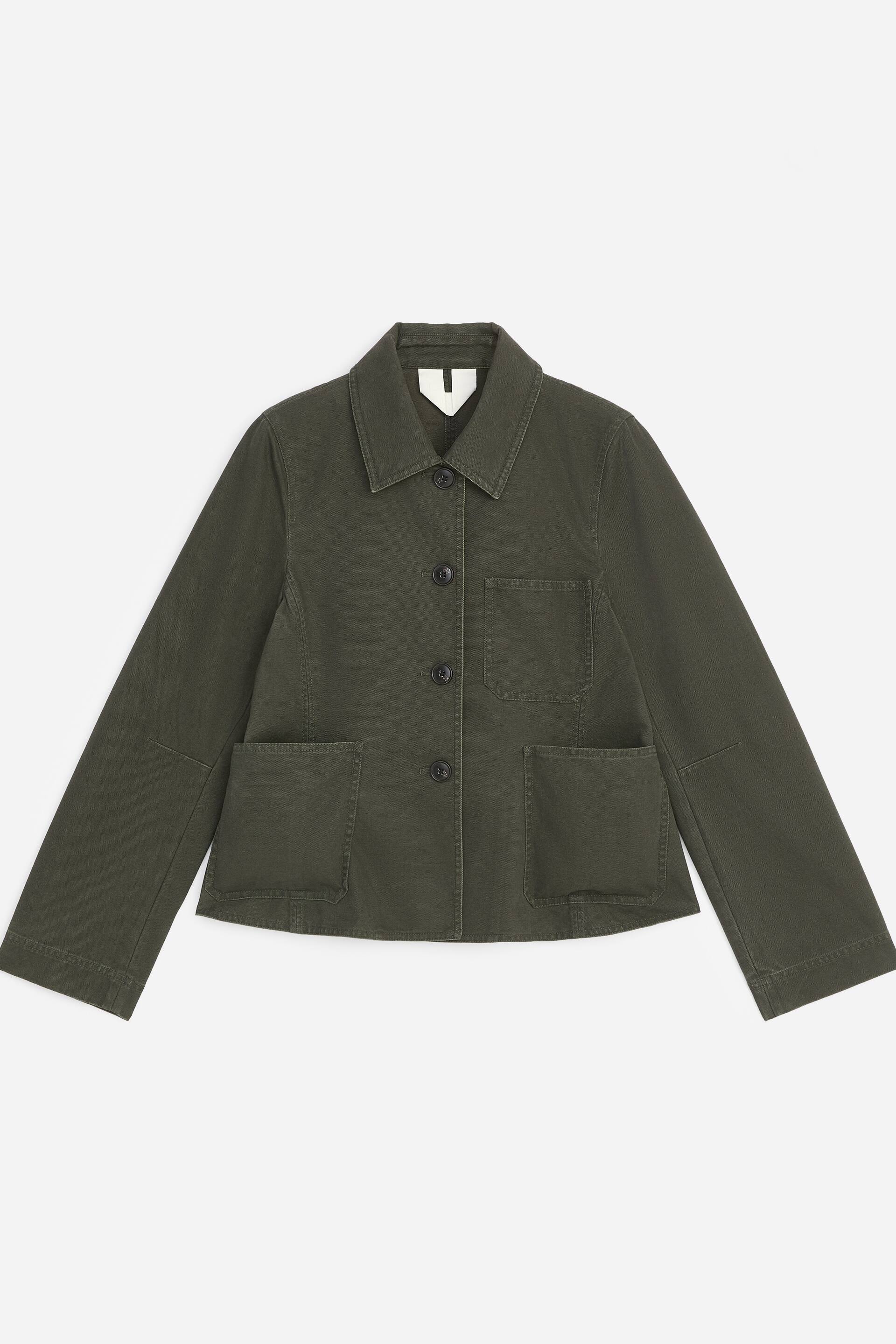 Visualizza l'immagine ingrandita: Questa giacca in tela di cotone verde scuro è mostrata in vista frontale, con una silhouette strutturata e un delicato fondo peplum. Presenta un classico colletto a punta, una chiusura frontale a quattro bottoni, una tasca applicata sul petto e due ampie tasche applicate inferiori.