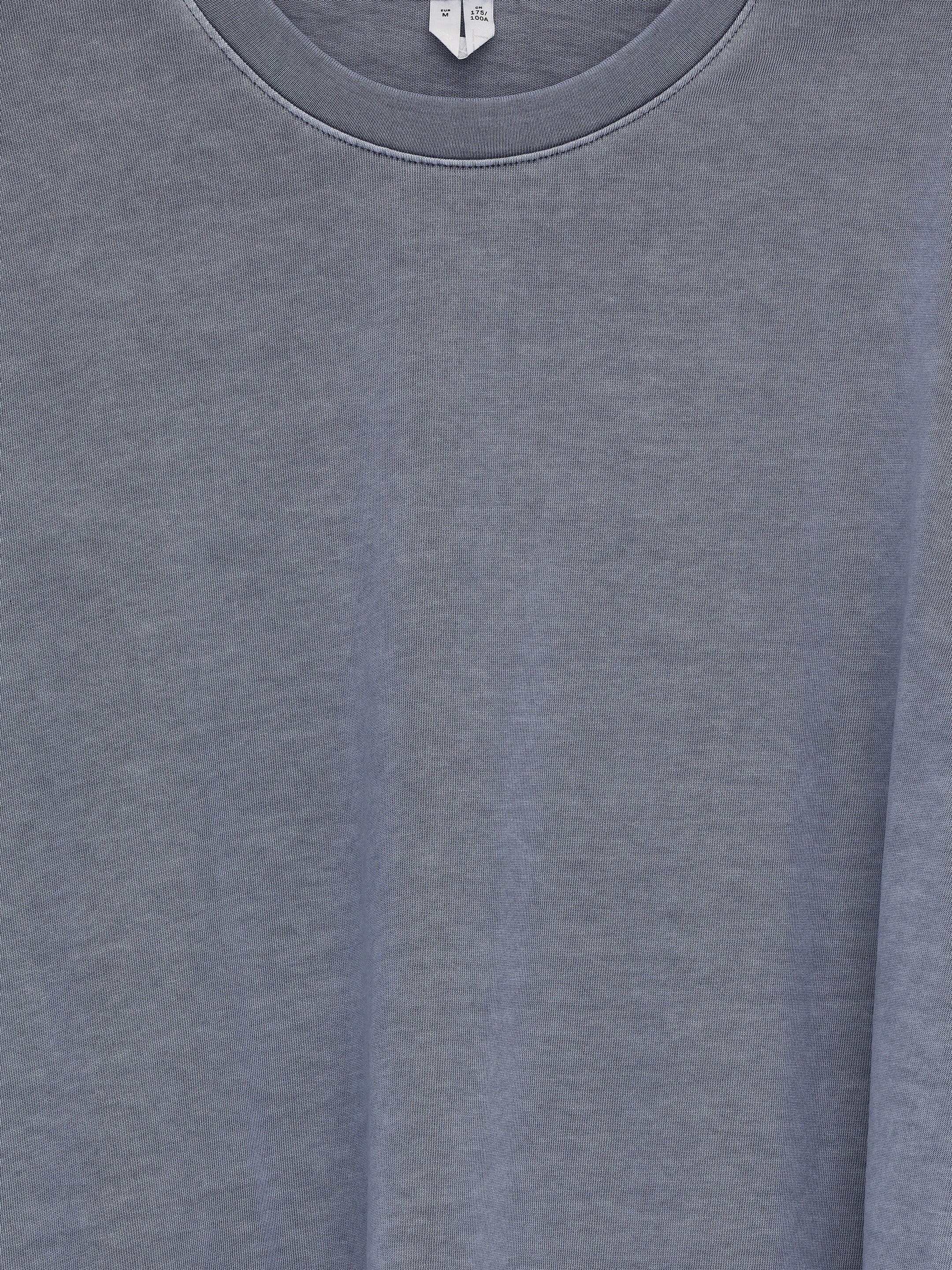 View larger image: A long-sleeved t-shirt is presented from the front, featuring a classic crew neck and a muted, washed-out grey color with a soft, cotton texture. A size label is visible at the back of the neck.