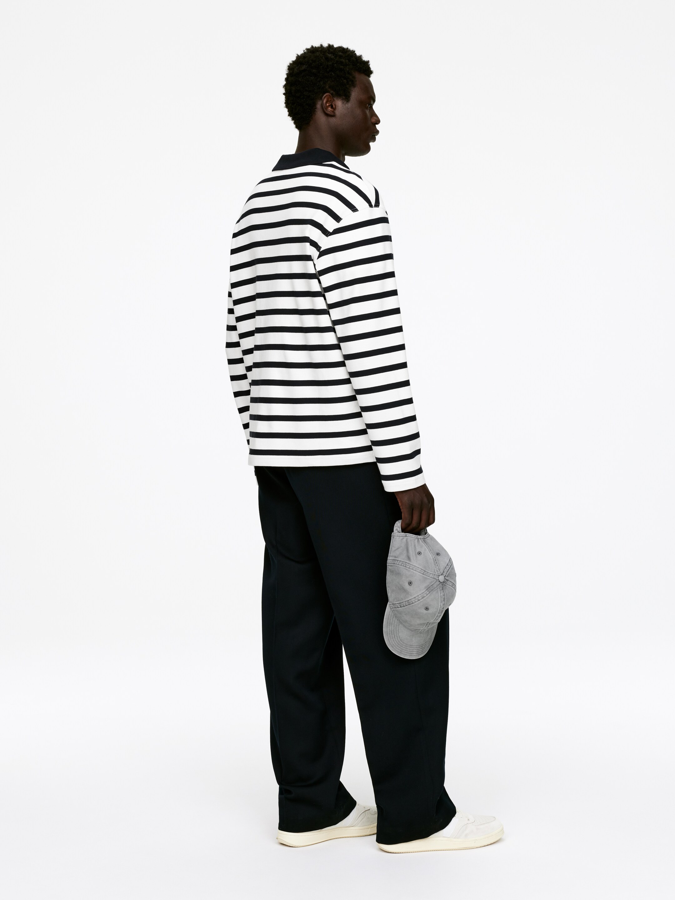 Se større billede: En langærmet, regular-fit polo shirt med sorte og hvide vandrette striber, en mørk ribbet krave og en halv placket bæres af modellen.