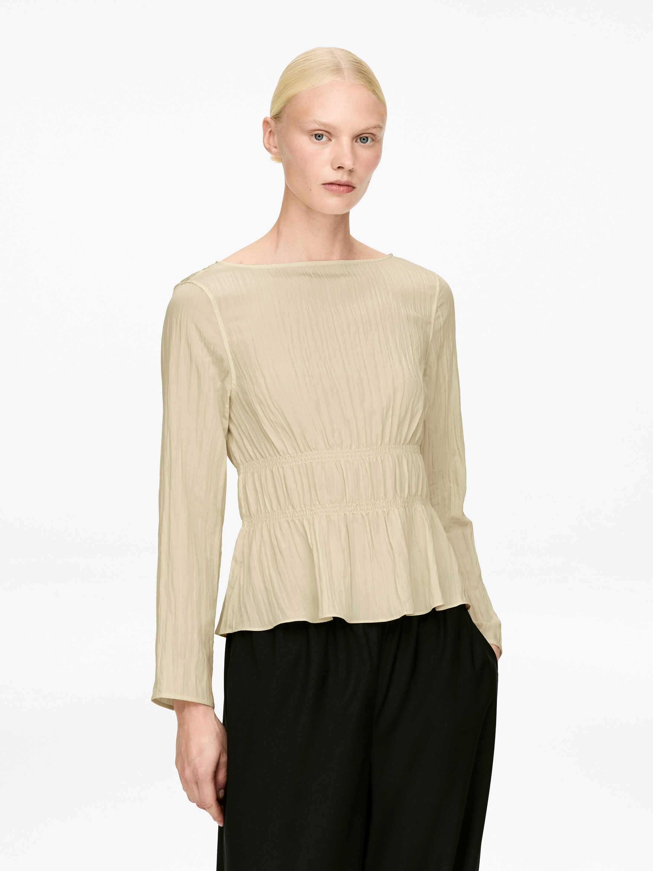View larger image: A light yellow long-sleeved top, made from a viscose blend, is being worn by the model. The top is featuring a wide neckline, a crinkled texture, and a smocked waist, creating a slim fit.