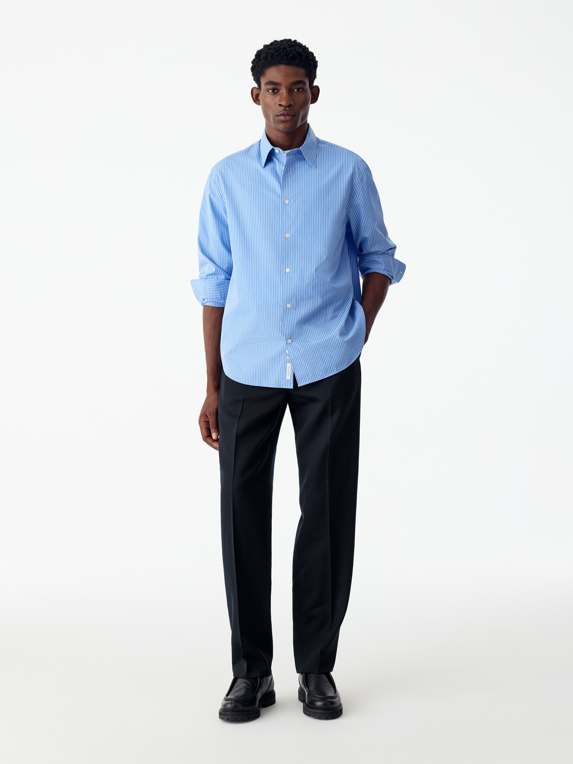 Questi pantaloni blu navy scuro sono appesi in una vista frontale, mostrando una silhouette a gamba dritta, una cintura strutturata con passanti per cintura e una chiusura frontale nascosta.