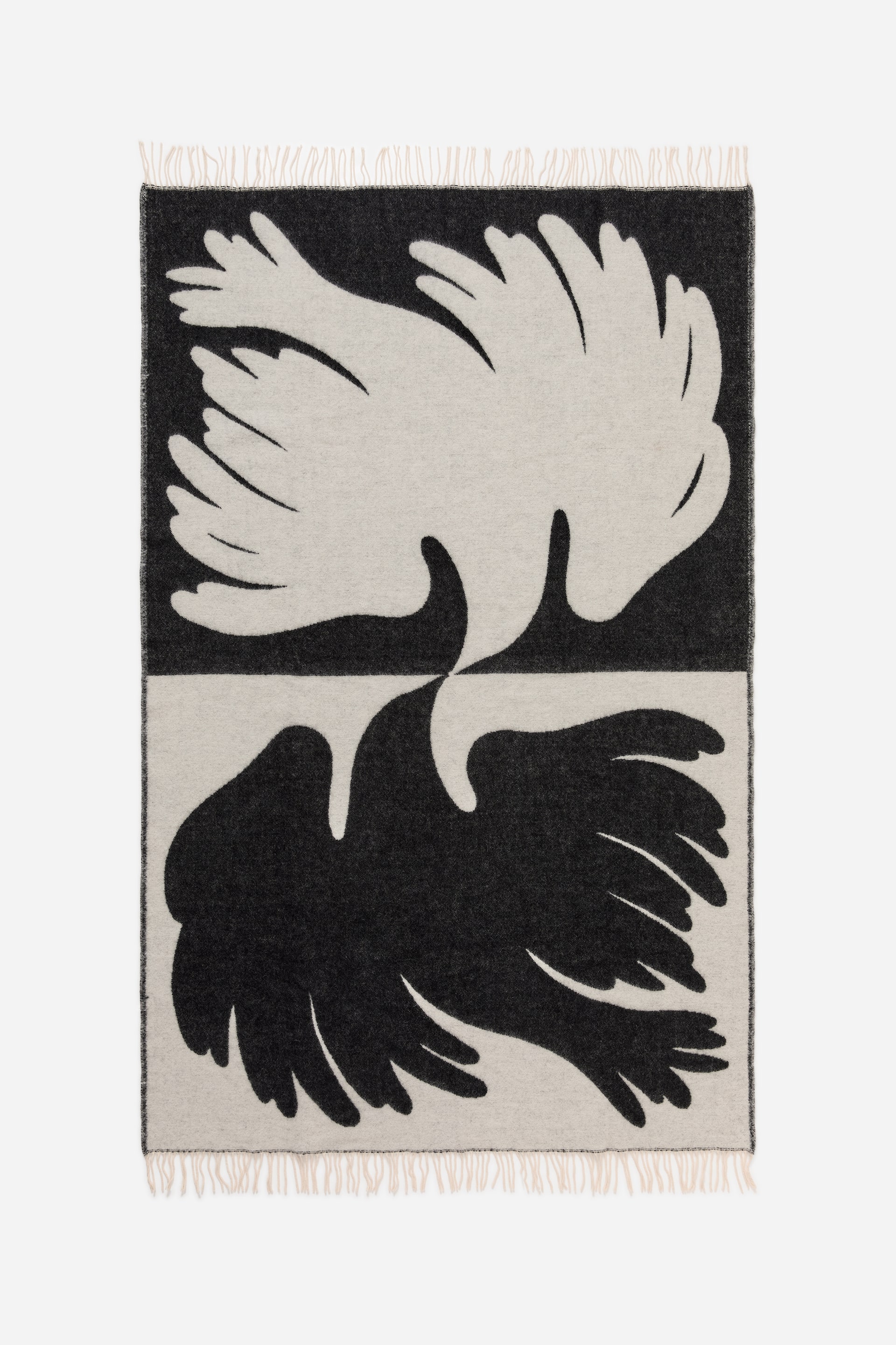 Visa större bild: En rektangulär pläd visar ett djärvt, tvåfärgat abstrakt mönster med vertikalt speglade organiska former i svart och ljusgrått. Den har fransade kanter längs dess övre och nedre del.