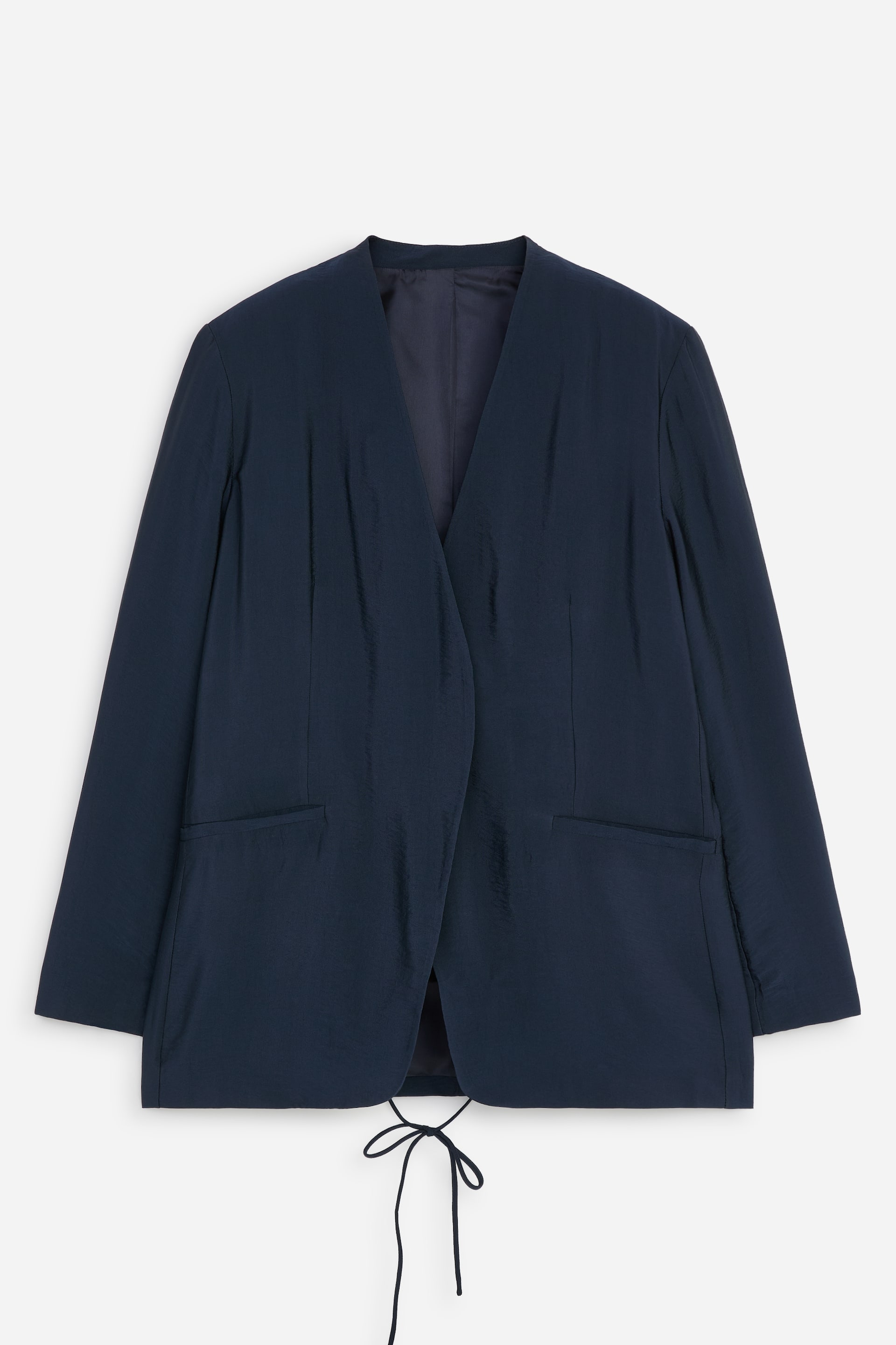 Agrandir l'image: Un blazer cache-cœur à coupe regular bleu marine est présenté de face, avec un col en V sans col et un tissu souple, légèrement froissé, à la brillance subtile. Deux poches passepoilées nettes sont visibles sur le devant, et une bride rouleau se noue en un nœud au bas du dos.