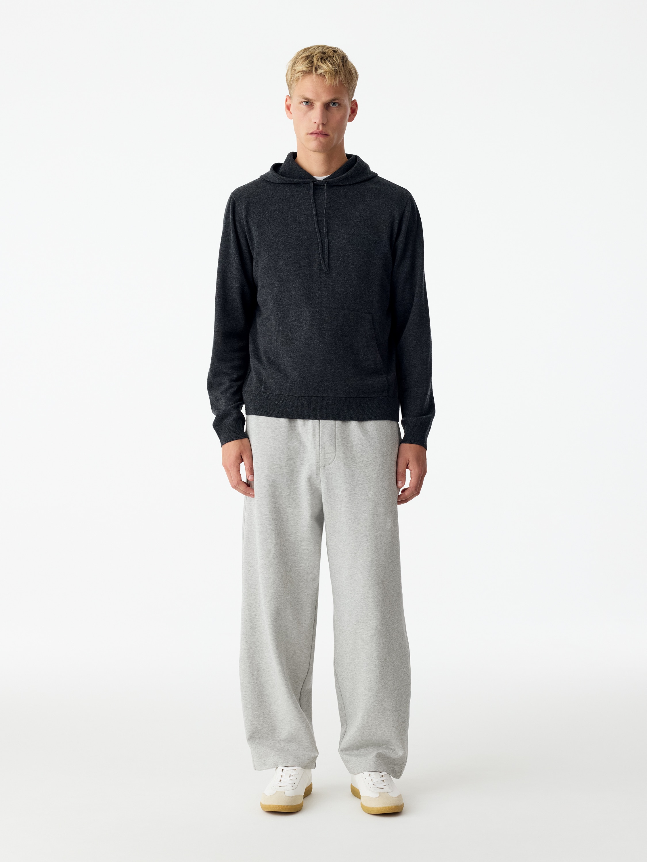 Een paar lichtgrijze, casual broeken is van voren weergegeven, met een elastische tailleband met verstelbaar trekkoord en een nep gulpdetail. De broek heeft een licht taps toelopend, wijde pijpsilhouet met steekzakken in de zijnaden.