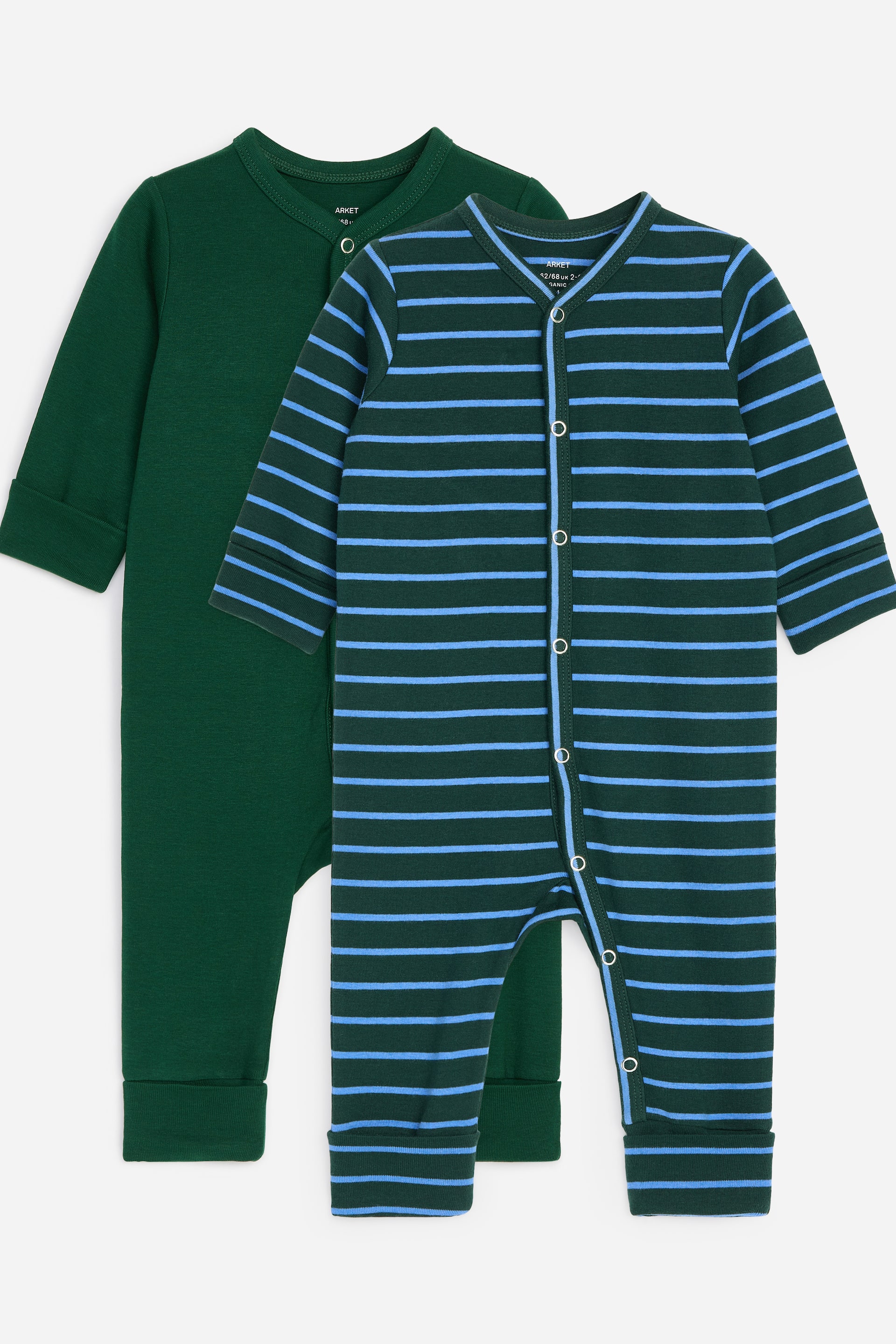 Visualizza l'immagine ingrandita: Un set di due tutine pigiama è mostrato dalla parte anteriore. Una tutina è di un colore verde scuro uniforme, mentre l'altra presenta un motivo a righe orizzontali verde scuro e azzurro chiaro. Entrambe sono caratterizzate da bottoni a pressione dalla testa ai piedi e polsini pieghevoli alle estremità delle maniche e delle gambe.