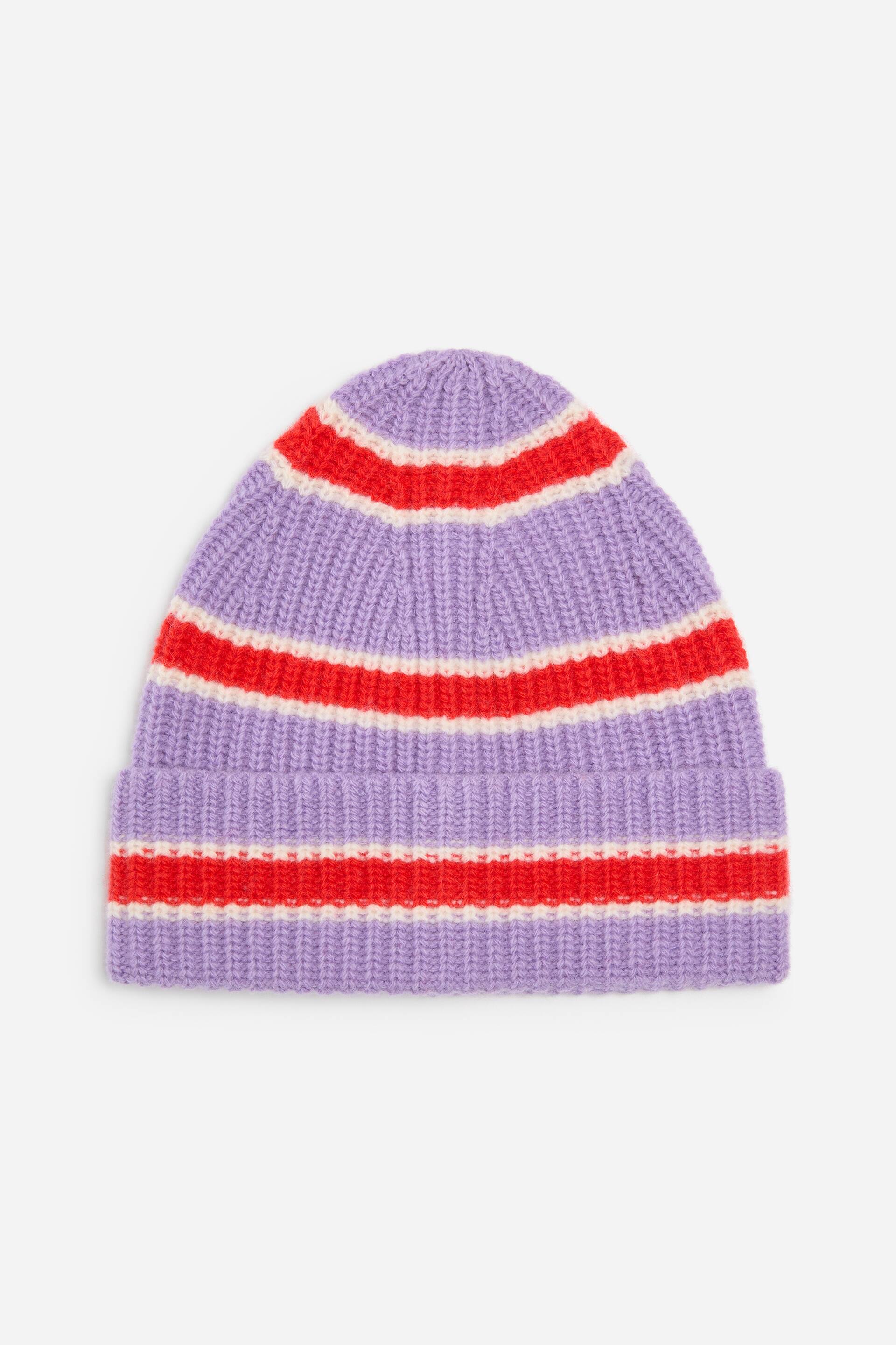 View larger image: A chunky rib-knitted beanie is shown from the front, featuring a light purple wool construction with horizontal red and white stripes. The beanie features a thick turn-up cuff and a rounded crown, showcasing its textured ribbed pattern.