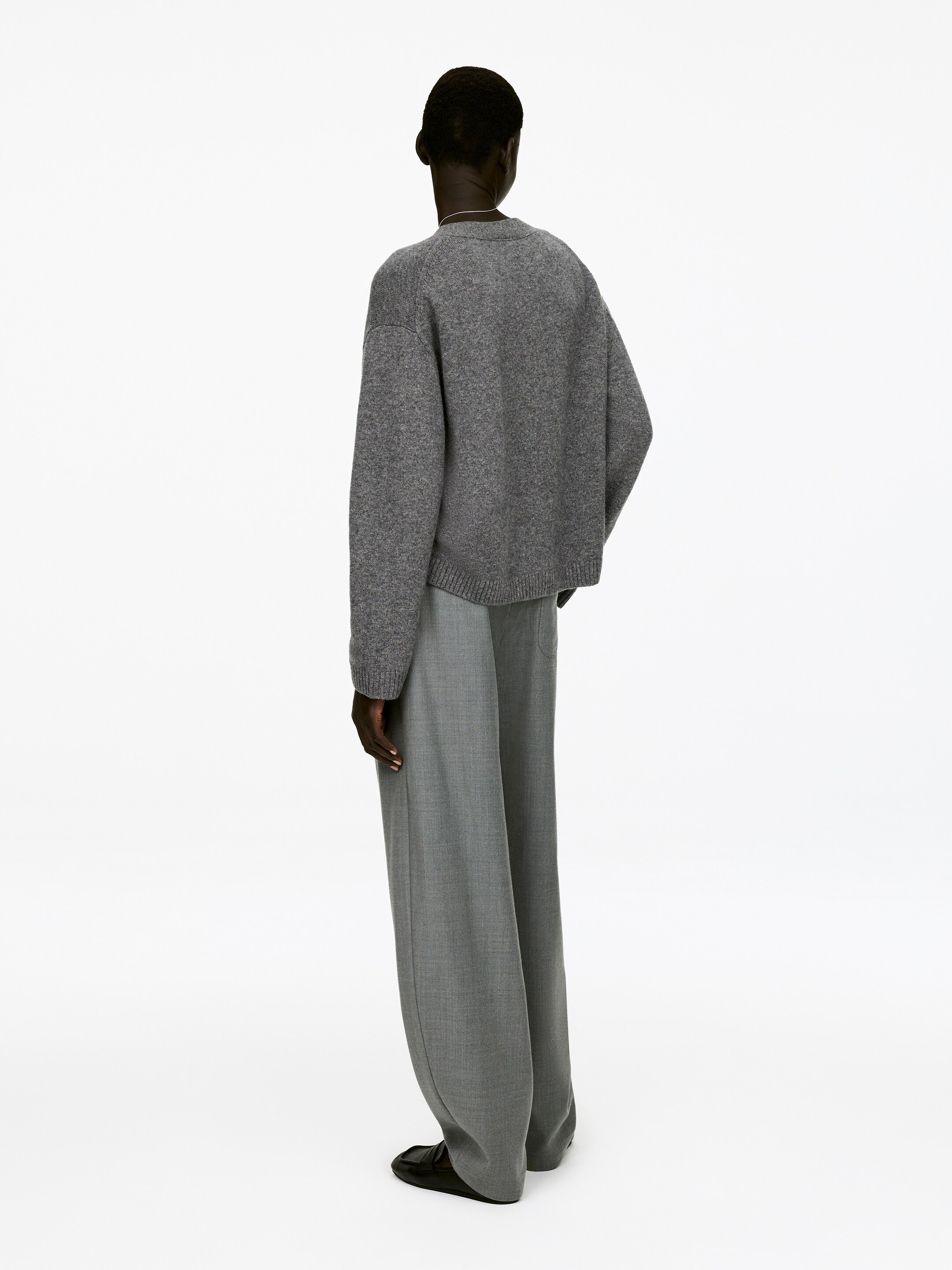 View larger image: A grey long-sleeved cardigan, featuring a visible rib-knitted hem, is being worn by the model, styled with grey wide-leg trousers.