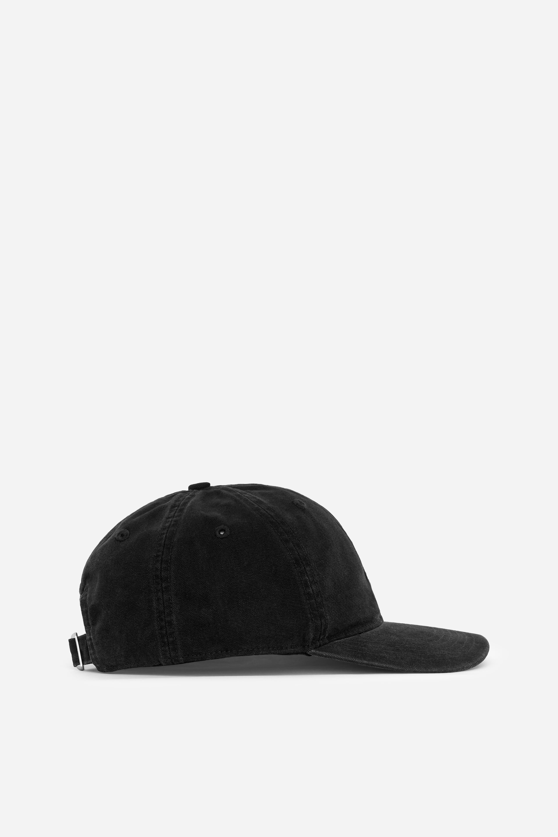 Agrandir l'image: Une casquette de baseball noire est présentée en vue latérale, dotée d'une visière incurvée et d'une couronne souple. Une lanière ajustable avec une boucle en métal argenté est visible à l'arrière, et le tissu présente un aspect légèrement délavé.