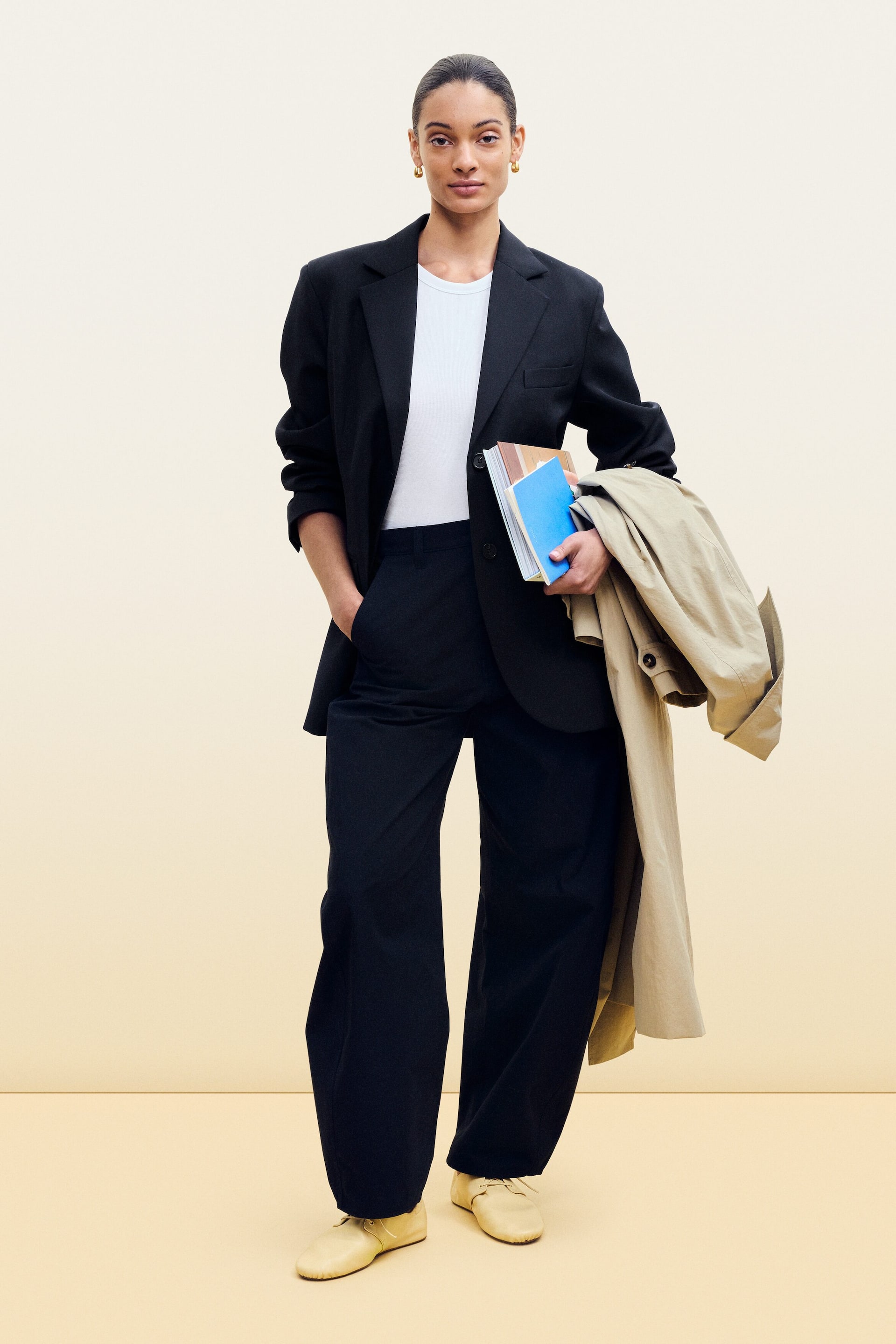 Zobacz większy obraz: Czarna marynarka jest noszona rozpięta na białym t-shircie, widoczna od przodu. Prezentuje szerokie ramiona, klapy w szpic oraz kieszenie z klapkami, a jej długie rękawy są lekko podwinięte.