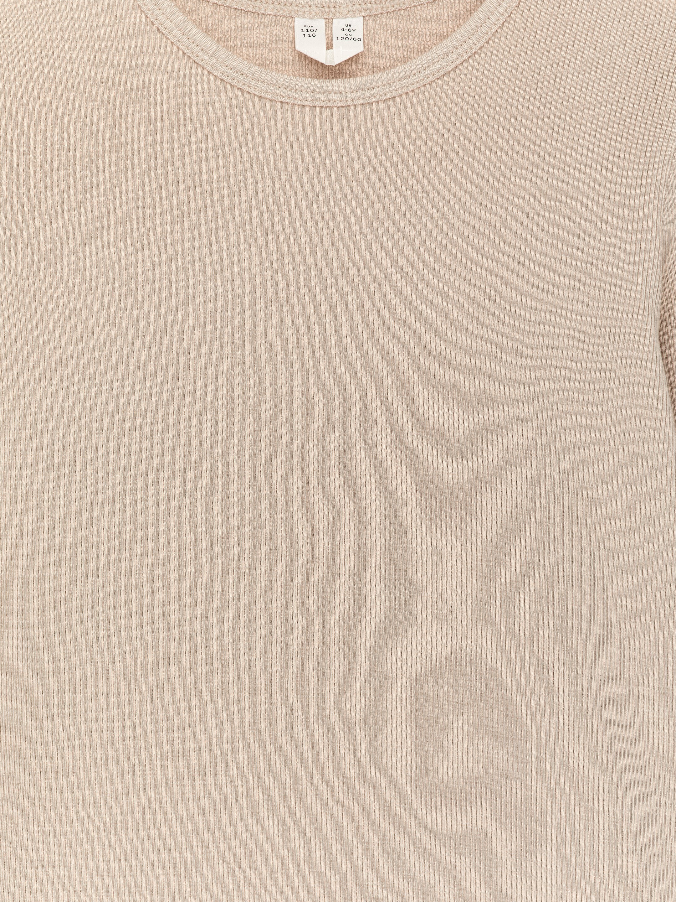 Agrandir l'image: Un T-shirt à manches longues avec une coupe ajustée est présenté de face. Il présente un col rond et exhibe un tissu en lyocell côtelé, beige et lustré.