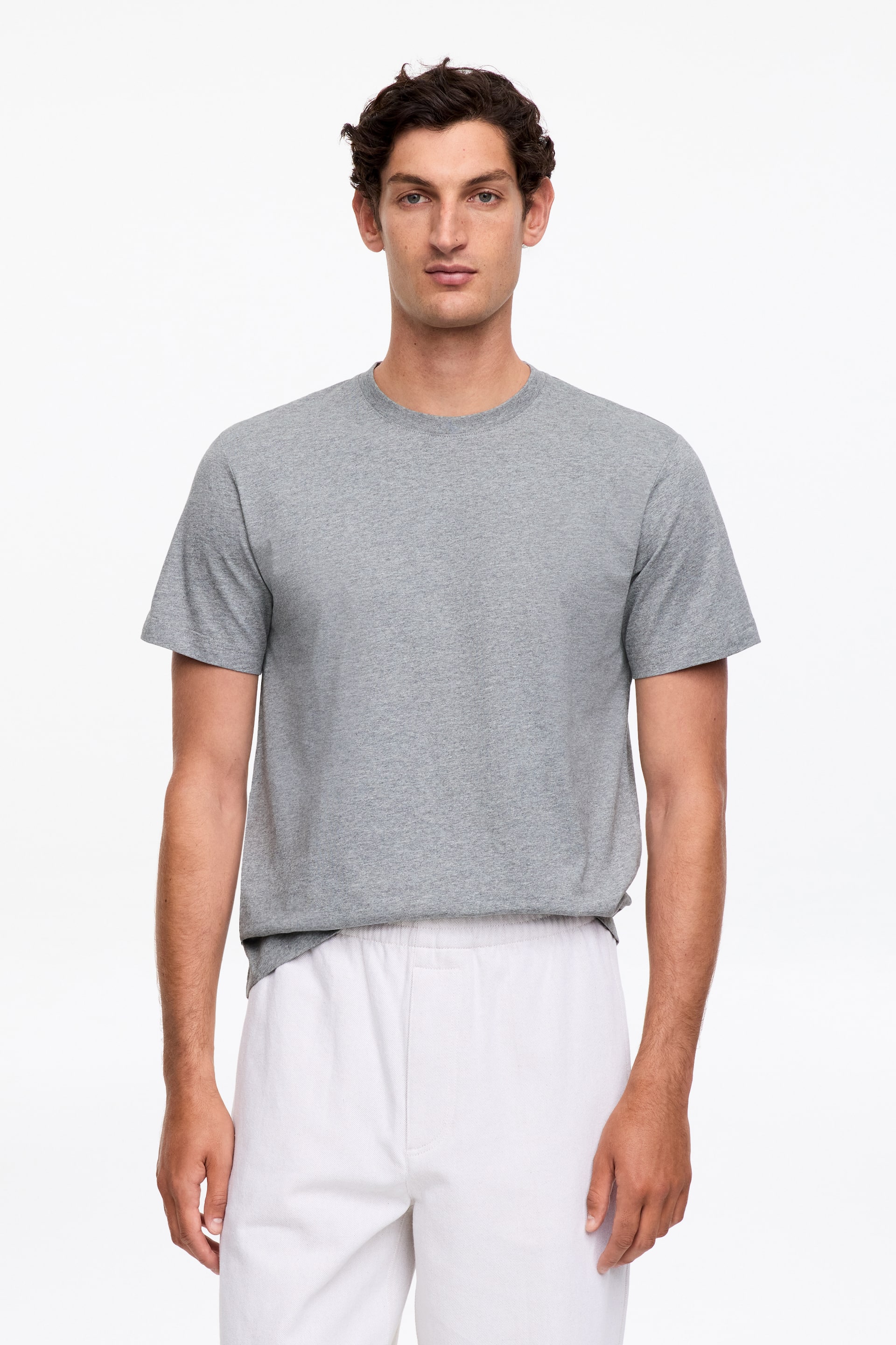 Visualizza immagine più grande: Una t-shirt girocollo grigio melange è presentata da un'angolazione frontale, con maniche corte e una vestibilità comoda.