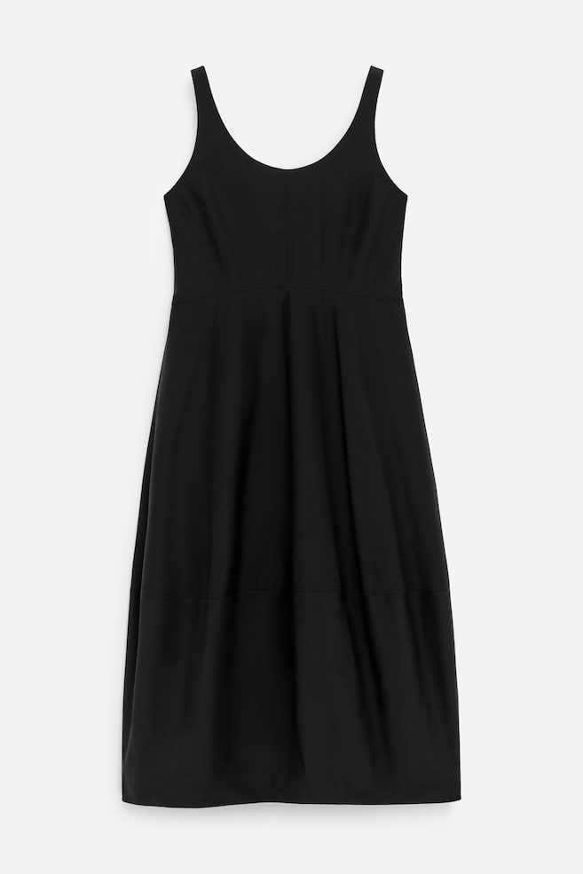 Un vestido negro sin mangas se presenta desde el frente, con un escote redondo y un corpiño ajustado. Su falda larga, de forma cilíndrica, muestra un detalle de costura horizontal por encima del dobladillo. - 1
