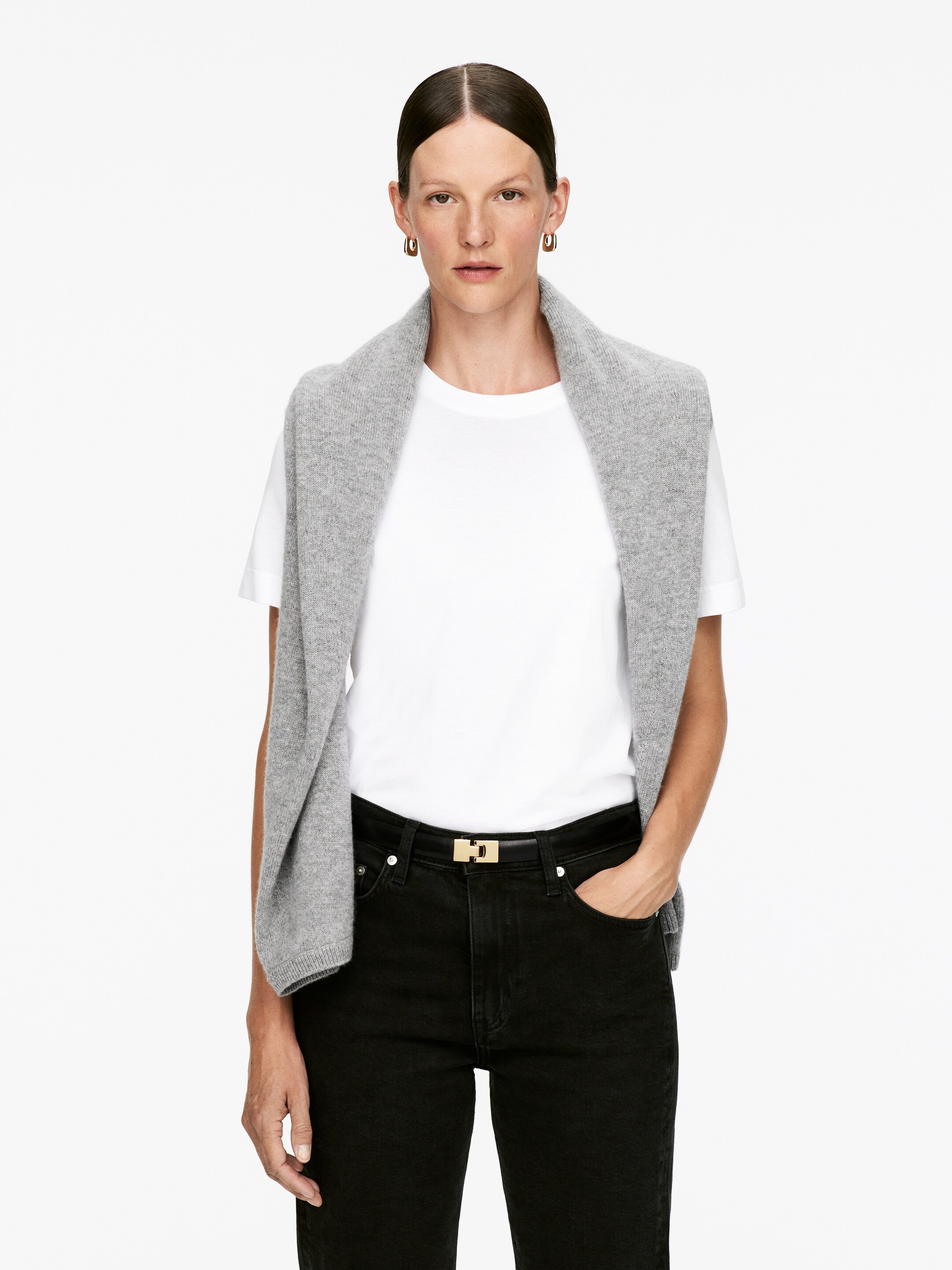 Agrandir l'image: Un pull gris clair est drapé sur les épaules, présenté de face. Il présente une texture en tricot doux et des poignets côtelés, porté sur un t-shirt blanc.