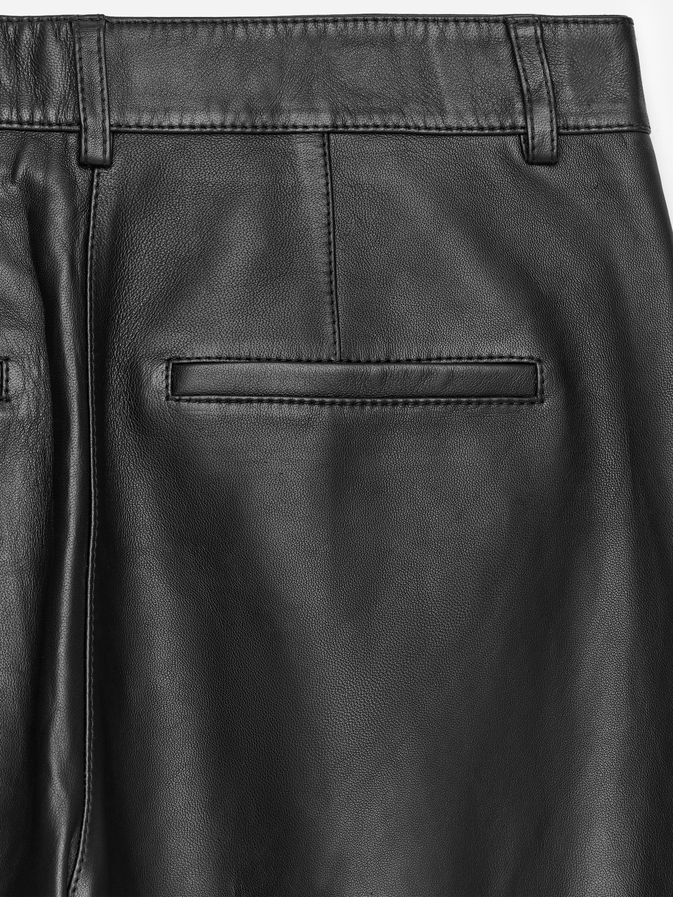 Visualizza immagine più grande: Pantaloni in pelle nera sono mostrati dal retro. Una cintura con passanti è visibile in alto, e una tasca a filetto orizzontale singola è visibile anche sul lato destro del retro. Cuciture verticali corrono lungo il capo.