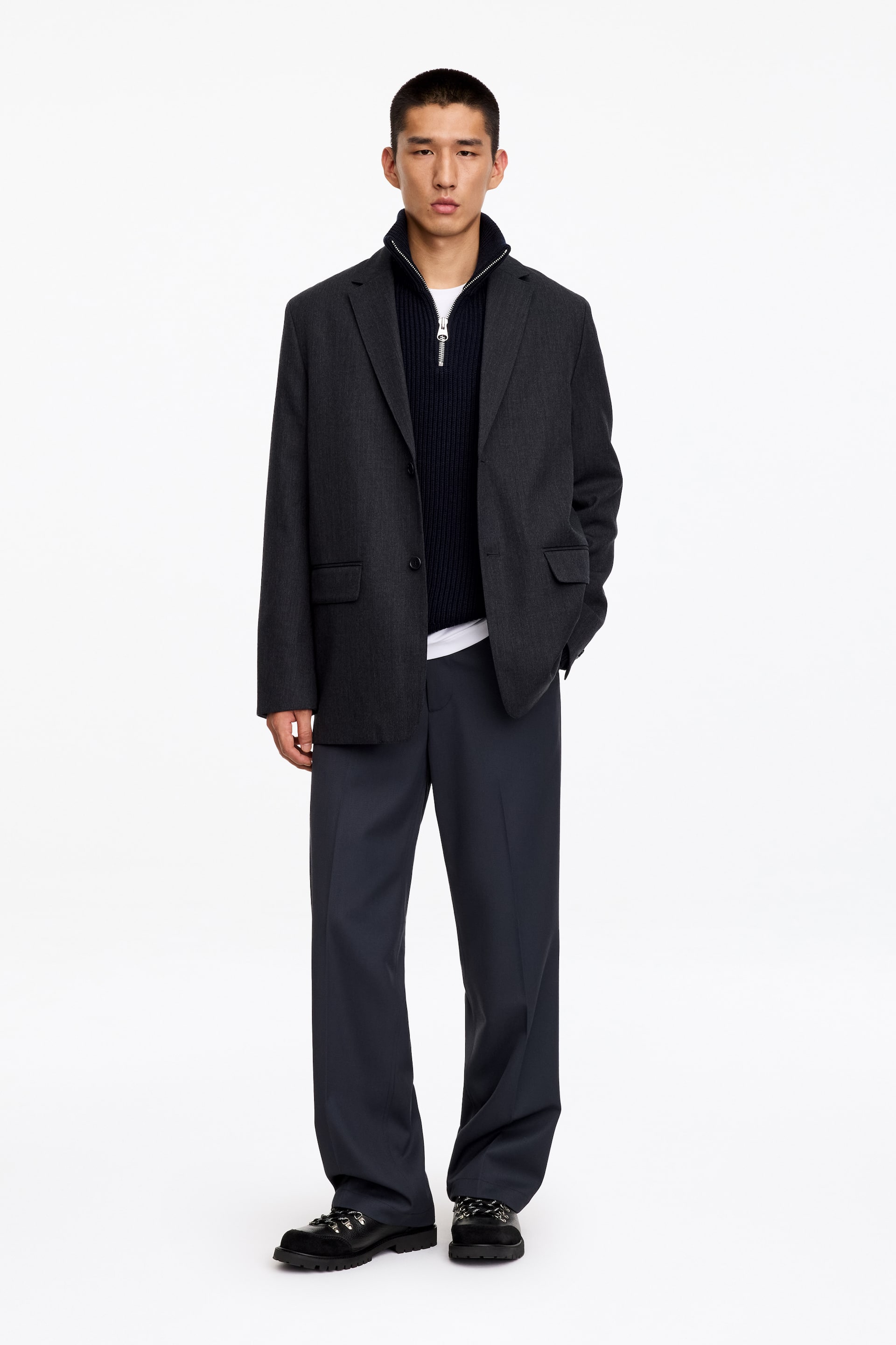 View larger image: Low-cut black hiking-style shoes featuring silver-tone metal eyelets, round laces, and a thick lugged rubber sole are being worn by the model. The shoes are paired with dark, wide-leg trousers that drape over the top of the footwear.
