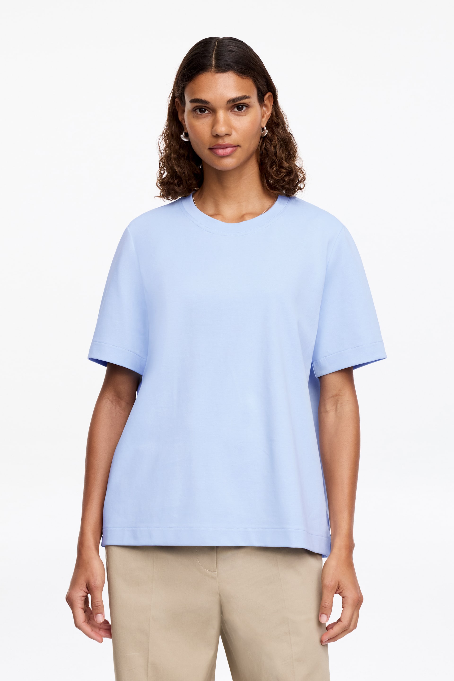 Grösseres Bild ansehen: Ein hellblaues T-Shirt wird von vorne präsentiert, mit einem Rundhalsausschnitt, kurzen weiten Ärmeln und einer lockeren Passform mit geradem Saum.