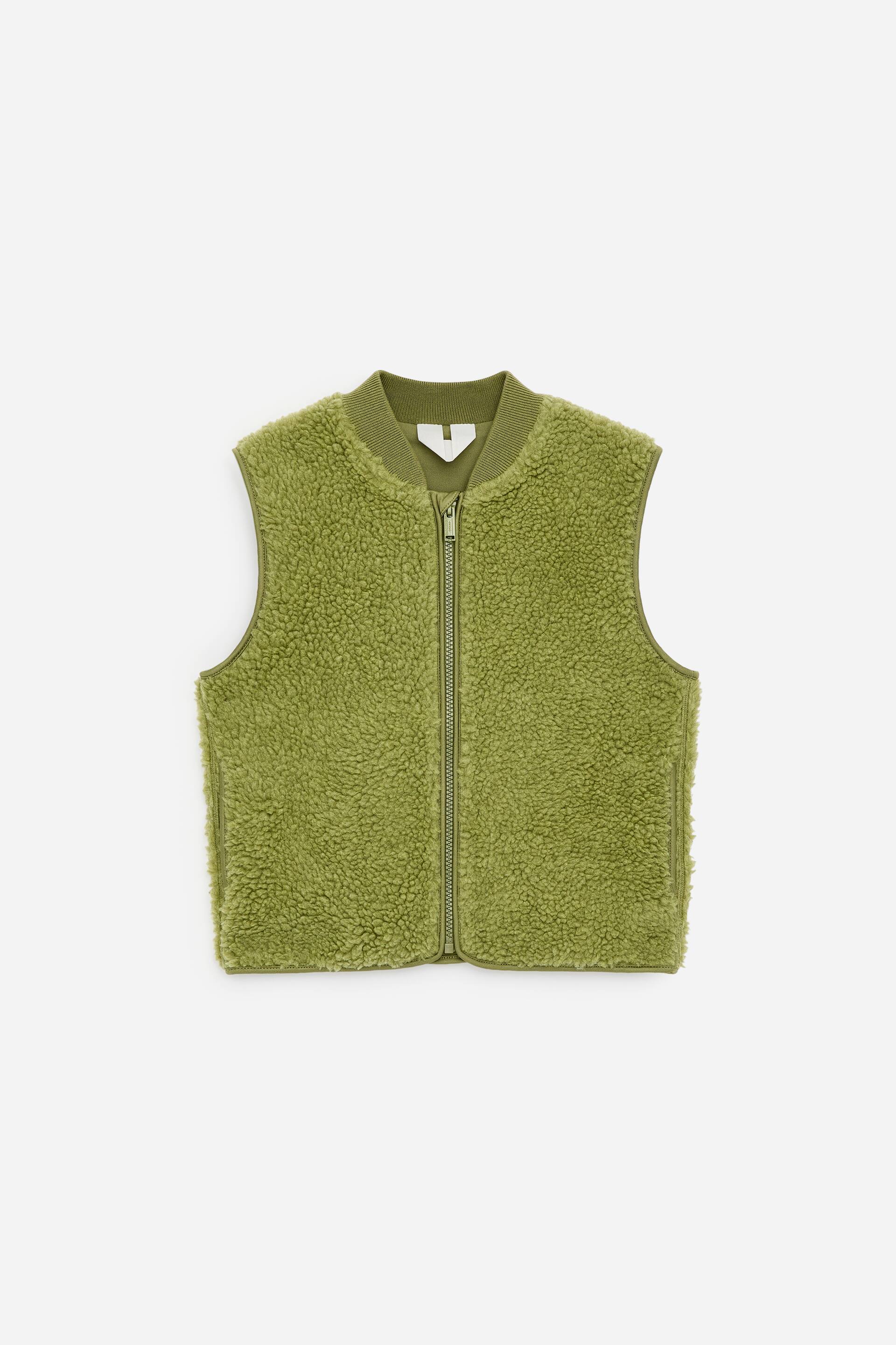 Visa större bild: En limegrön sherpa fleeceväst visas framifrån, med en dragkedja i full längd. Den visar också upp en ribbad ståkrage, ribbade ärmhålskanter, ribbad nederkant och två vertikala sidofickor.