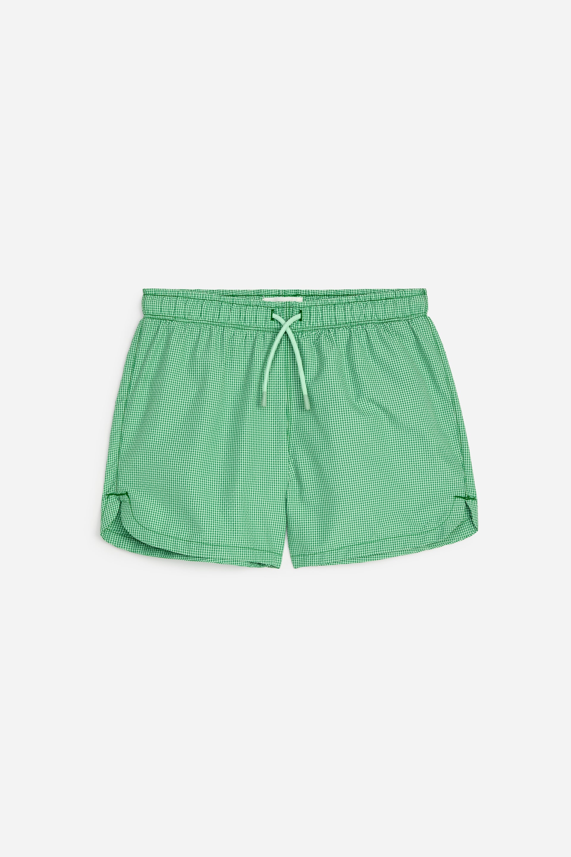 Ver imagen más grande: Los bañadores muestran un patrón de cuadros vichy en verde y blanco, vistos de frente. Cuentan con una cintura elástica con cordón ajustable y dobladillos laterales curvados.