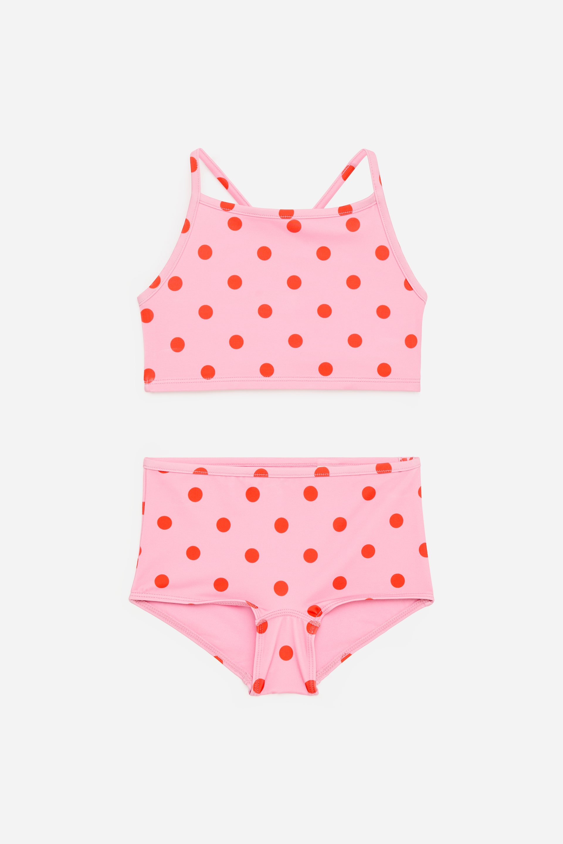 Ver imagen más grande: Un conjunto de bikini de dos piezas se presenta en vista frontal, con un color base rosa y lunares rojos. La parte superior es de estilo cuello alto con tirantes finos, y la parte inferior son pantalones cortos de talle alto tipo "boy shorts".