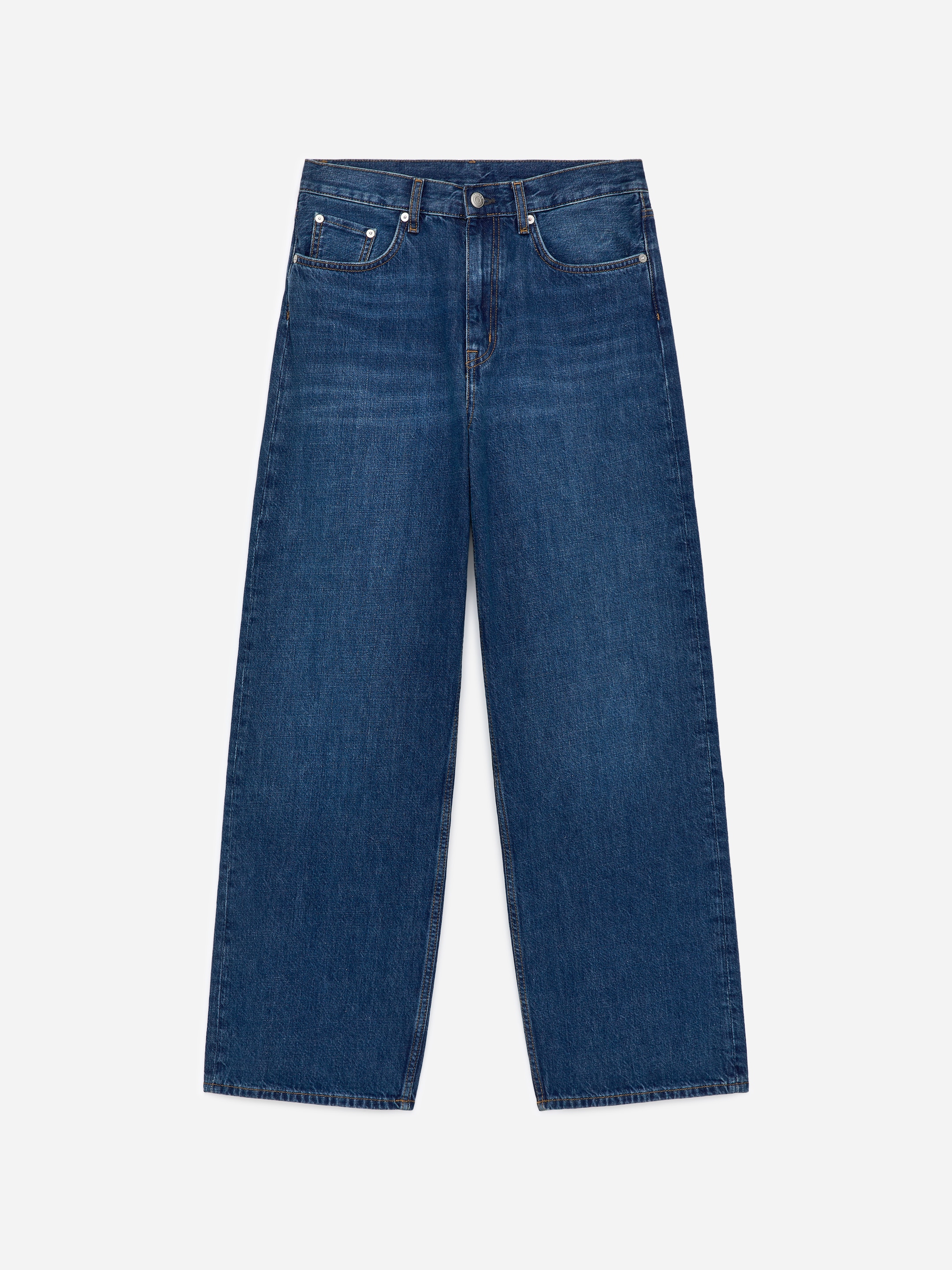 Zobacz większy obraz: Para ciemnoniebieskich dżinsów leży płasko, przodem do widza. Charakteryzują się wysokim stanem, szerokimi nogawkami i luźnym krojem, z widocznymi przednimi kieszeniami, kieszonką na monety i szlufkami na pasek.