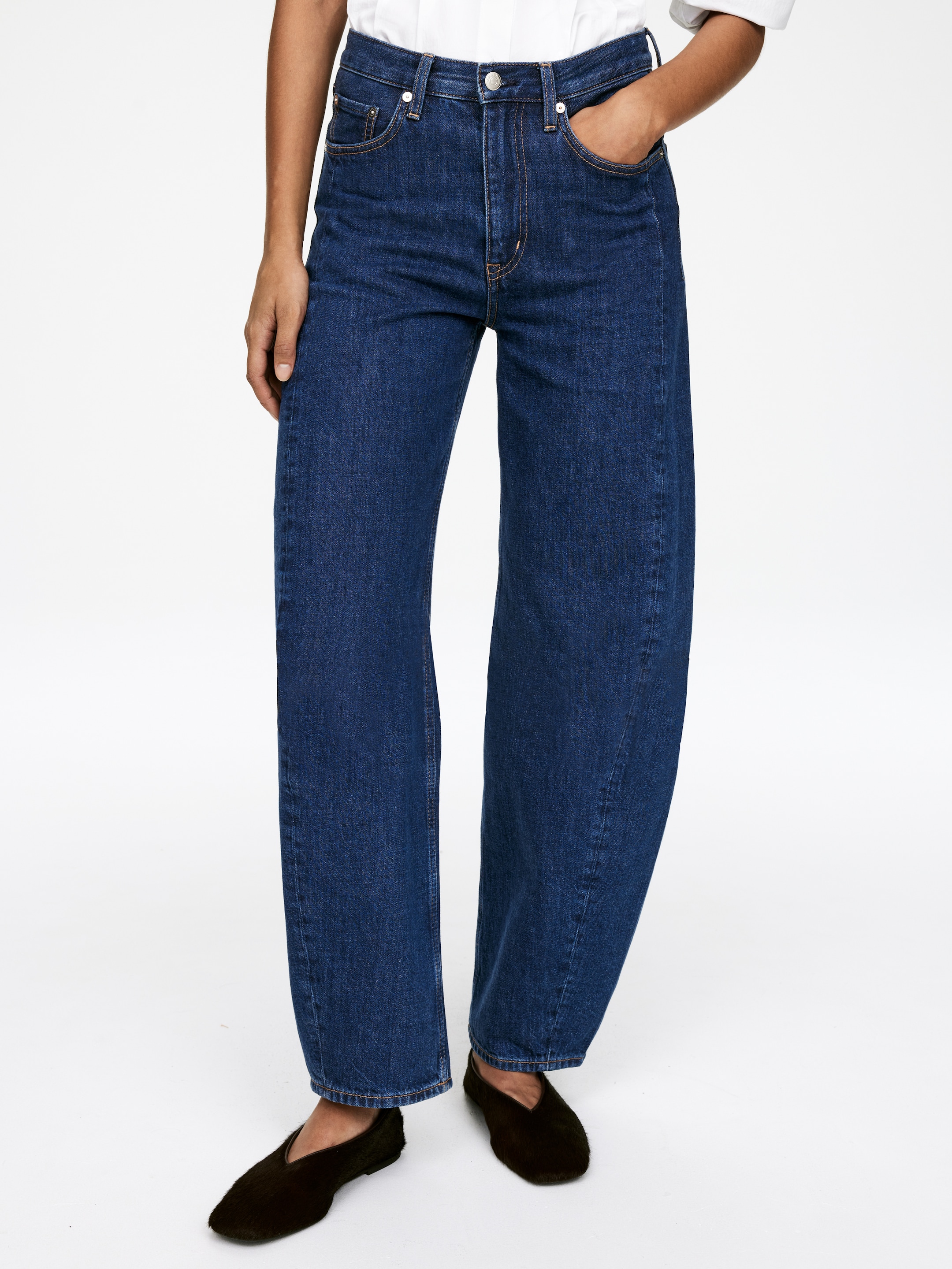 View larger image: Dark blue denim jeans are being presented from a front view, featuring a high waist, visible belt loops, and a button and zip fly closure with classic five-pocket styling. The jeans are showcasing a relaxed, wide-leg fit that extends to a full length, slightly gathering at the ankles.