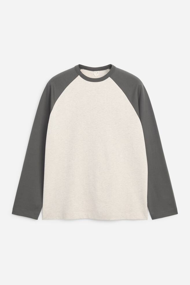 A front view of a baseball T-shirt showcases a classic colour-blocked design with a light-grey textured body and contrasting dark-grey long raglan sleeves. The shirt features a matching dark-grey rib-knitted crew neck and a straight hem. - 1