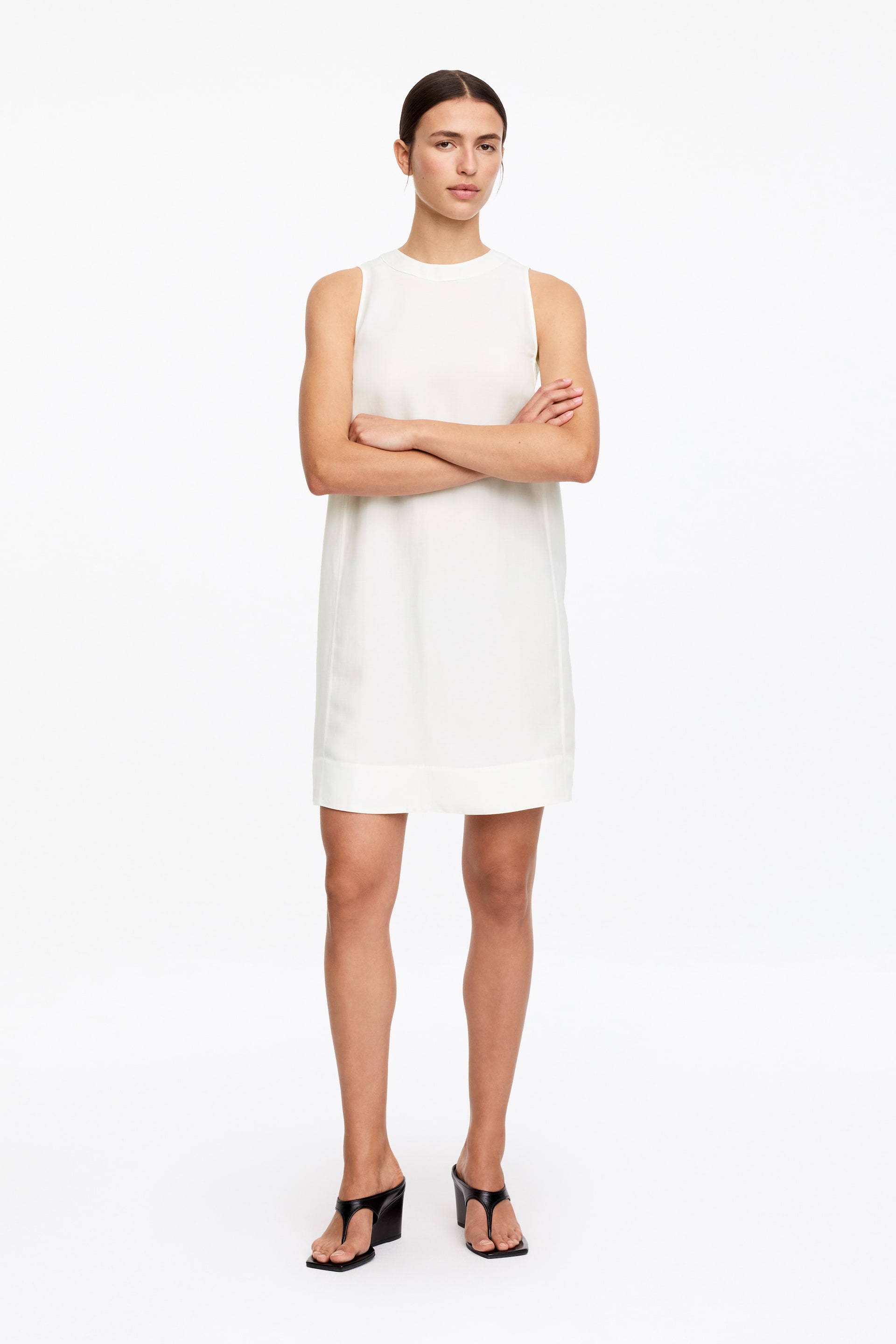 Agrandir l'image: La robe droite sans manches blanche présente un col rond et une silhouette droite au-dessus du genou.