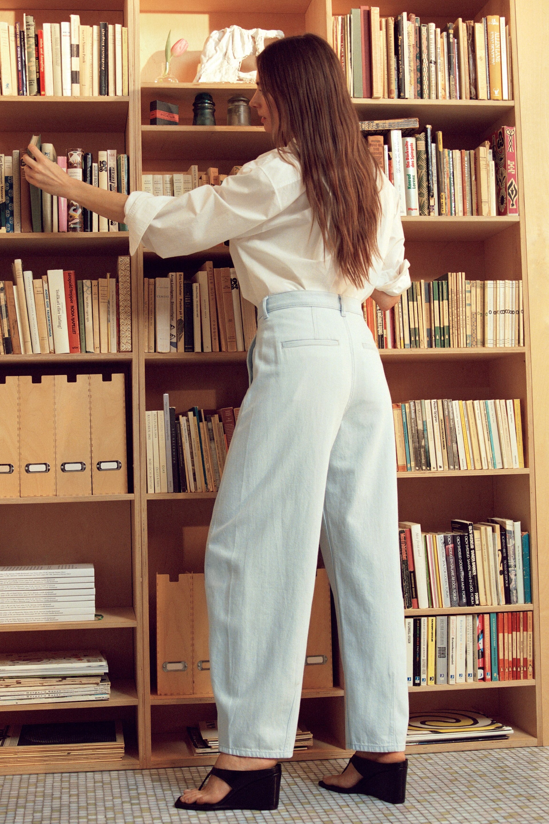 Visualizza immagine più grande: Jeans a gamba larga in lavaggio chiaro con vita alta e tasche posteriori visibili, che offrono una silhouette rilassata vista da dietro.