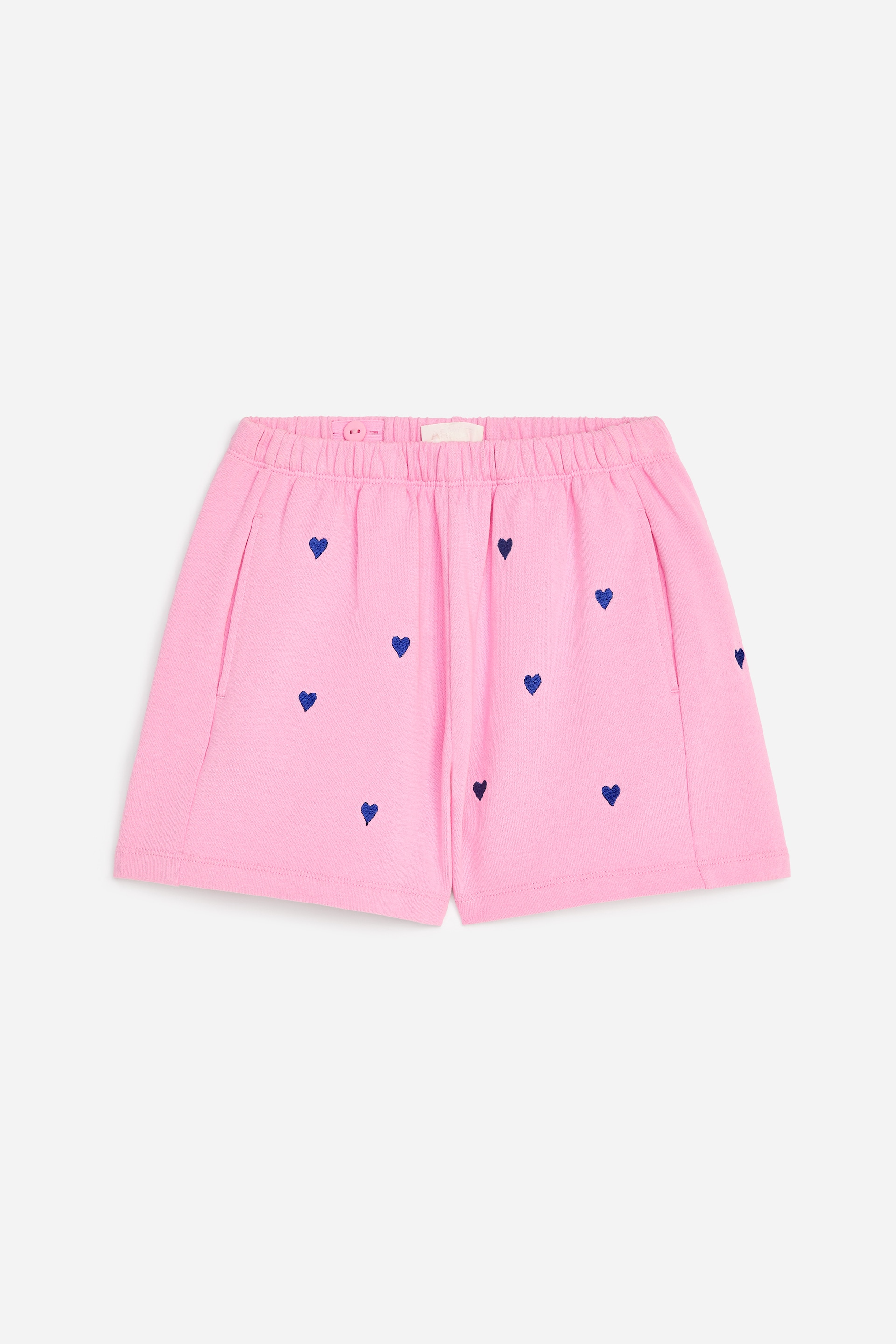 Se større billede: Lyserøde shorts med elastisk talje og et mønster af små blå hjerter over det hele. To sidelommer er synlige, og shortsene har en afslappet pasform.