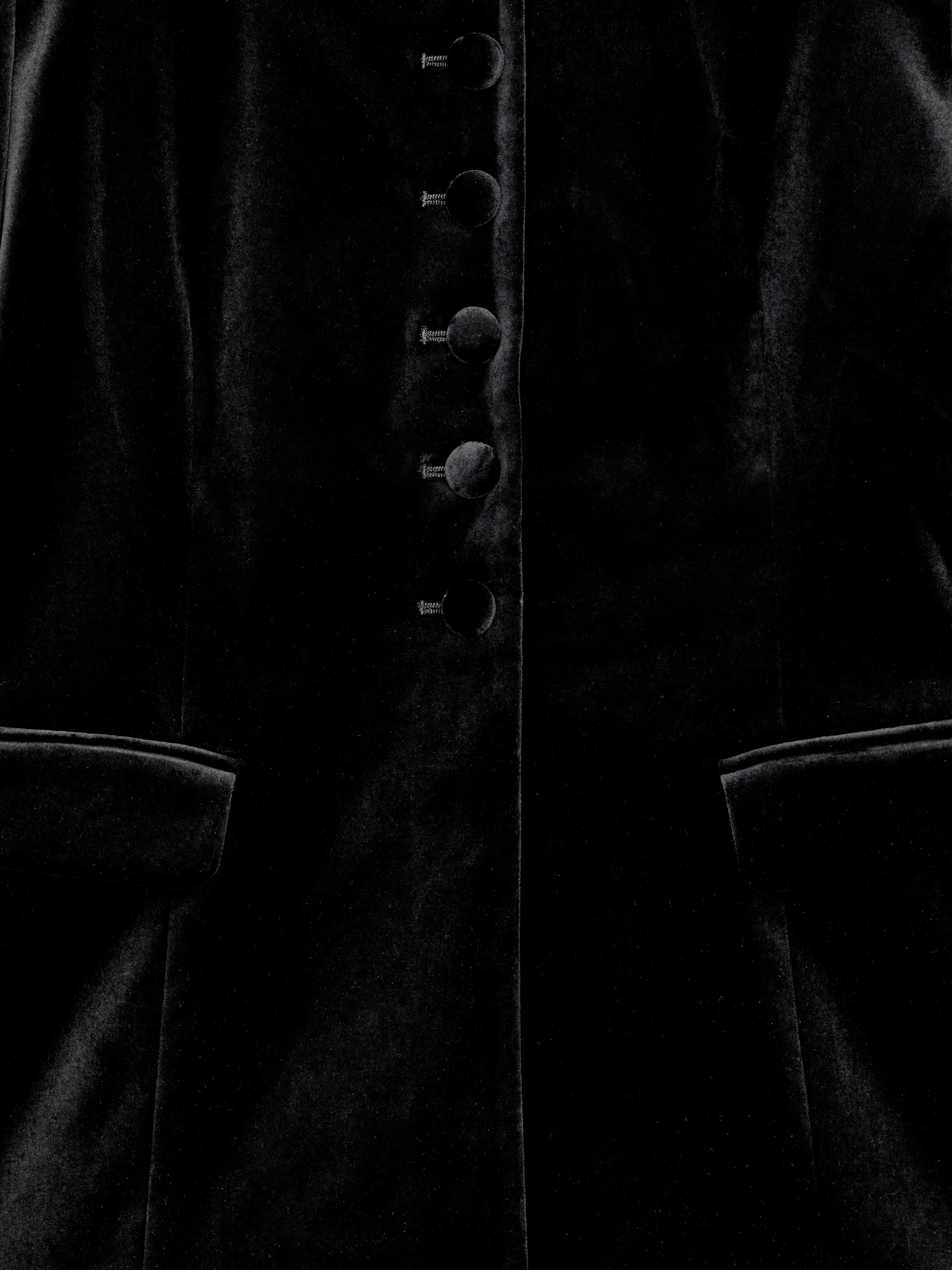 Ver imagen más grande: Se presenta un blazer negro de terciopelo sin cuello, que cuenta con un cierre frontal de botones con cinco botones cubiertos de tela. El detalle de pinzas da forma a su ajuste entallado, y los bolsillos con solapa son visibles en la parte inferior delantera.