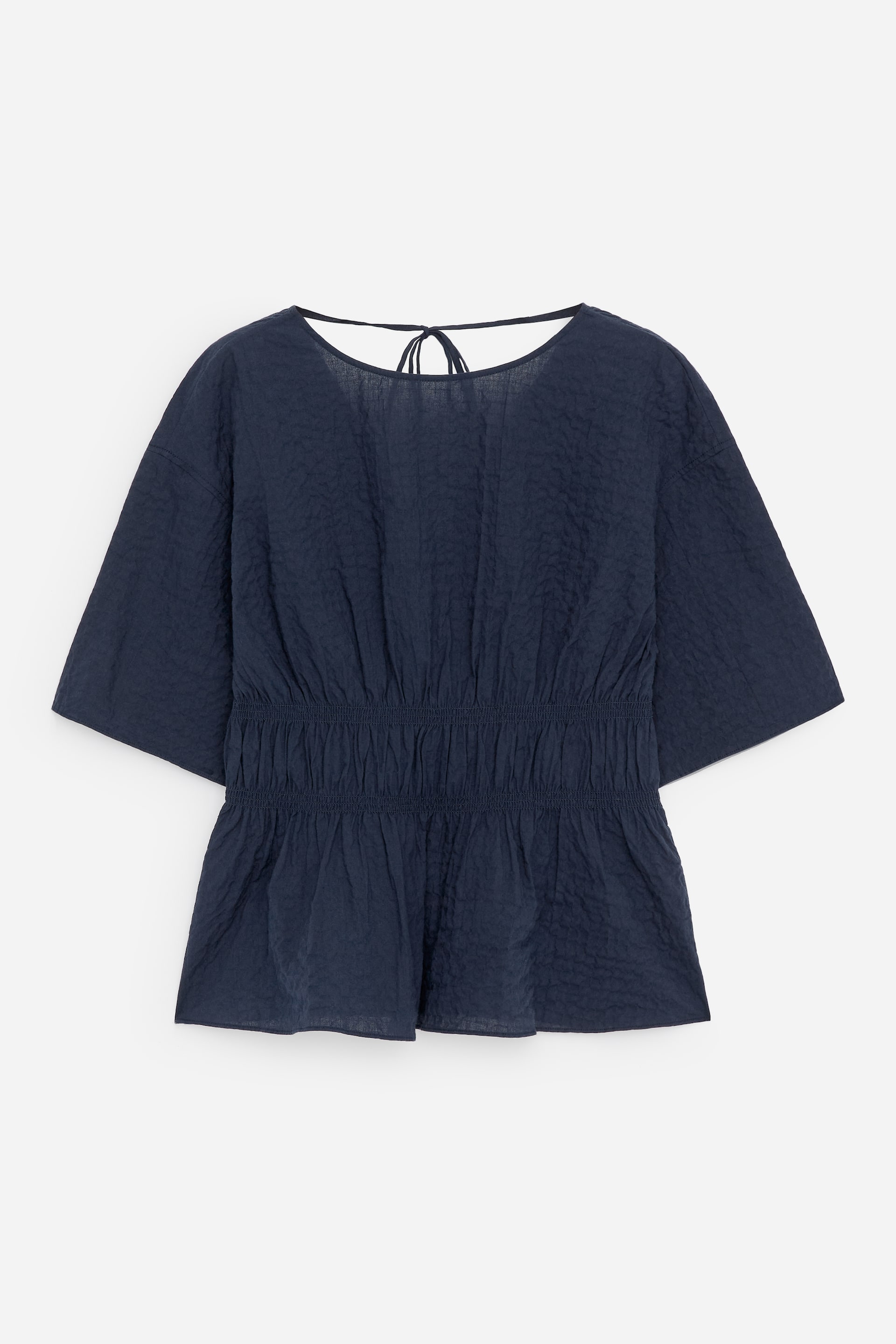 View larger image: A dark blue crinkled top is shown FRONT, featuring a round neckline with a tie detail visible at the back. It is designed with short, wide sleeves and an elasticated, shirred waist that flares into a peplum hem.