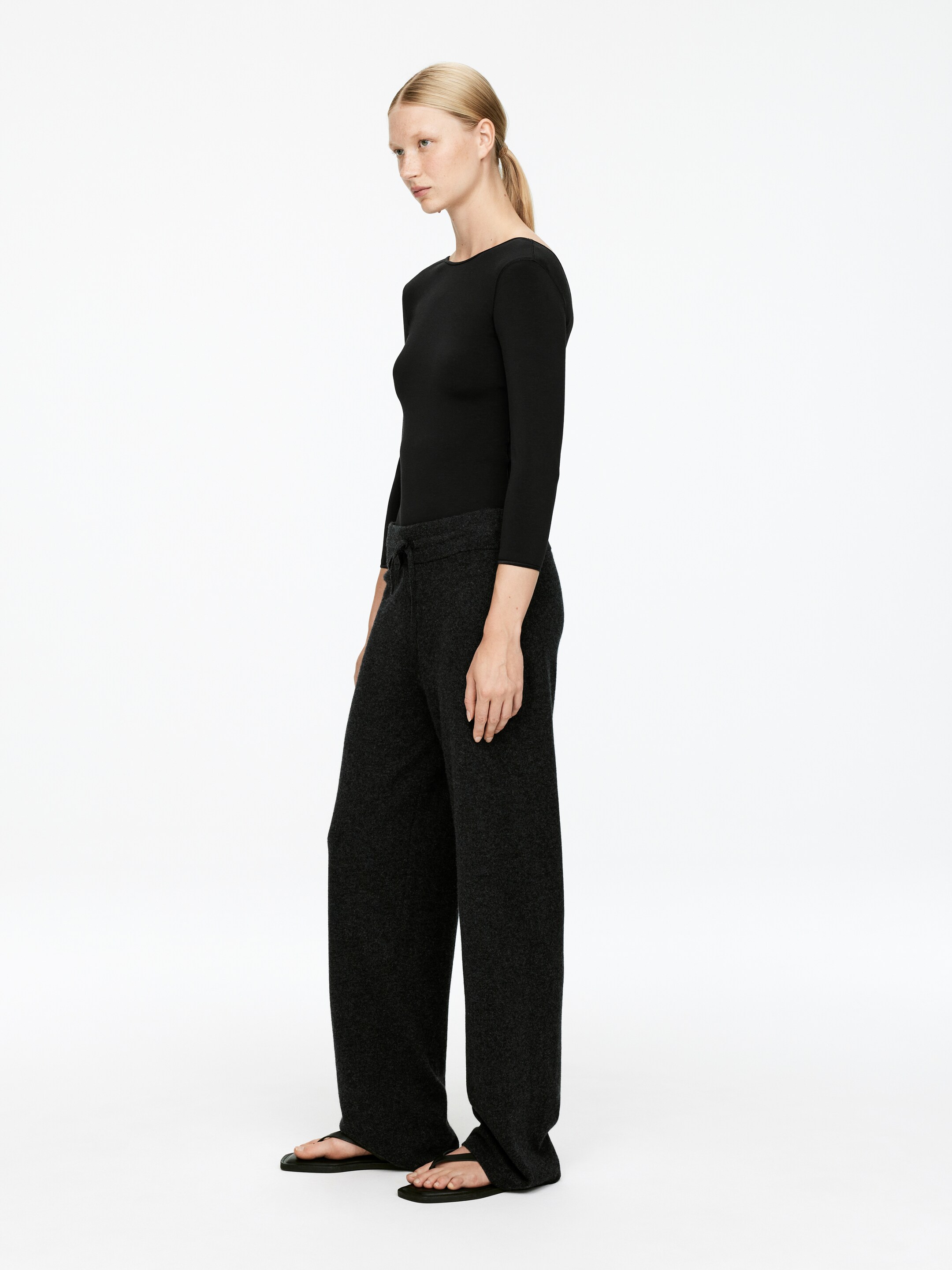 View larger image: A black, slim-fit bodysuit with three-quarter sleeves is being worn by the model. It is being styled with dark grey wide-leg trousers.