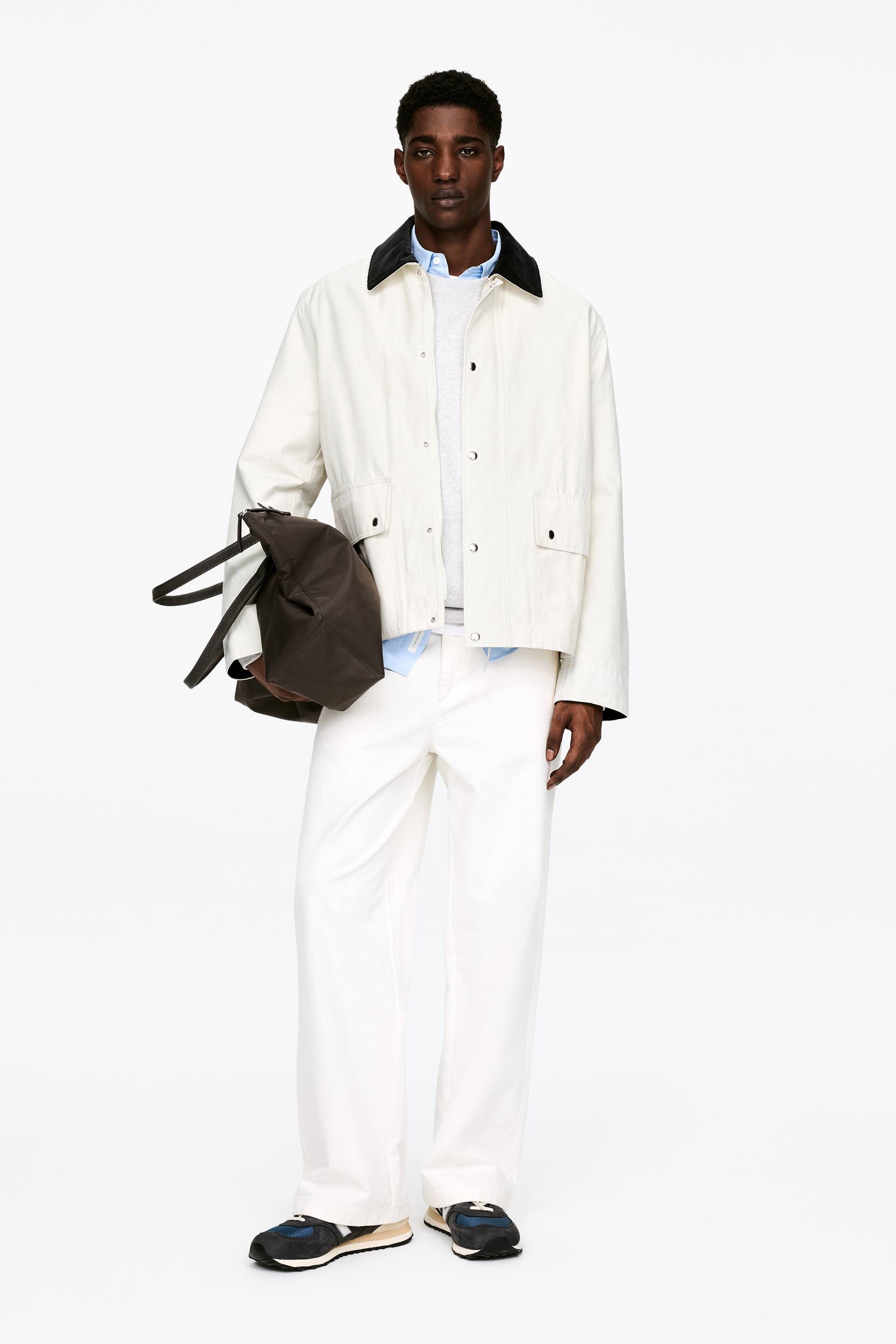 Agrandir l'image: Une veste blanc cassé orientée vers l'avant présente un col noir contrastant et une fermeture à boutons-pression sur le devant. Elle arbore deux grandes poches plaquées à rabat sur le bas du devant et offre une coupe décontractée.