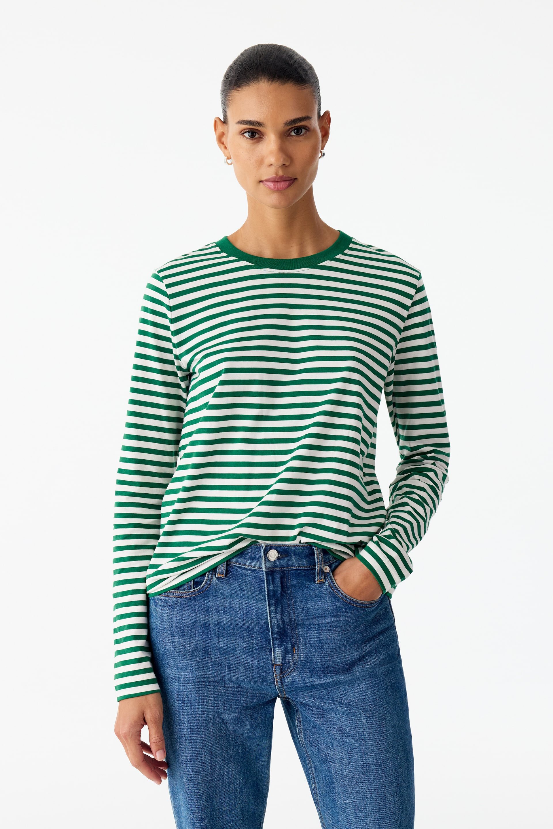 Vezi imaginea mai mare: Modelul poartă un tricou cu mânecă lungă, cu dungi orizontale verzi și albe, și cu guler rotund verde uni, din material rib cu bordură. Modelul asortează cămașa cu croială regular fit cu blugi din denim albastru, având o mână băgată în buzunar.